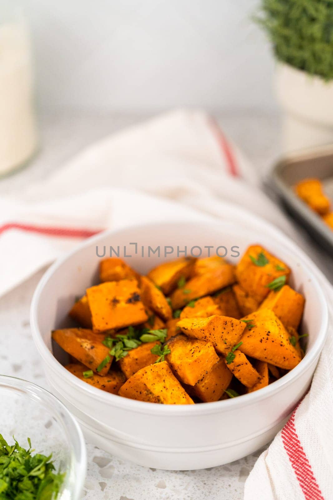 Serving oven-roasted sweet potatoes in a white ceramic bowl.