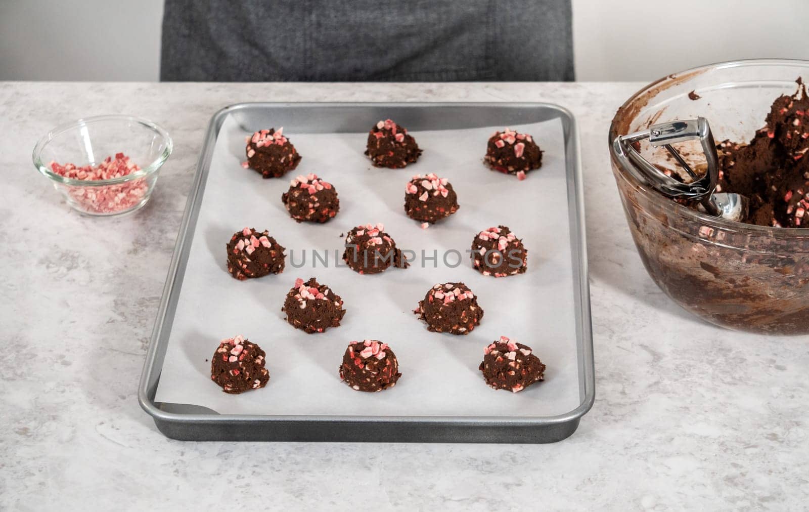 Scooping chocolate cookie dough with dough scoop to bake chocolate cookies with peppermint chips.