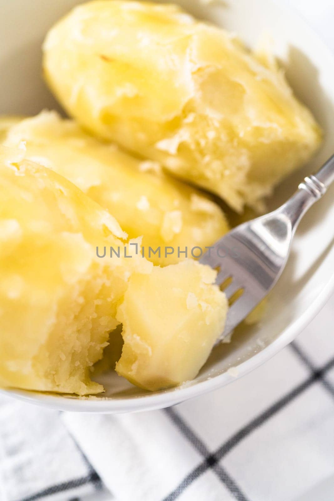 Mashed potatoes. Cooking whole peeled potatoes in a white bowl.