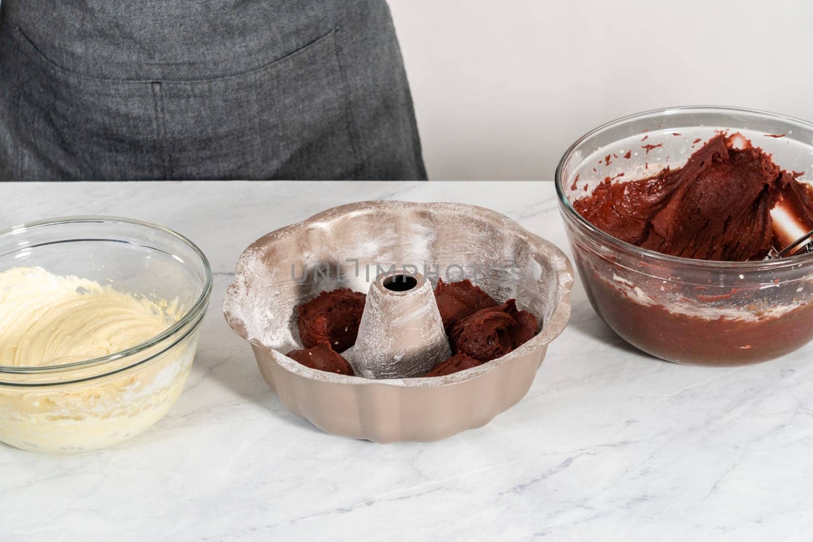 Filling metal bundt cake pan with cake butter to bake red velvet bundt cake with cream cheese glaze