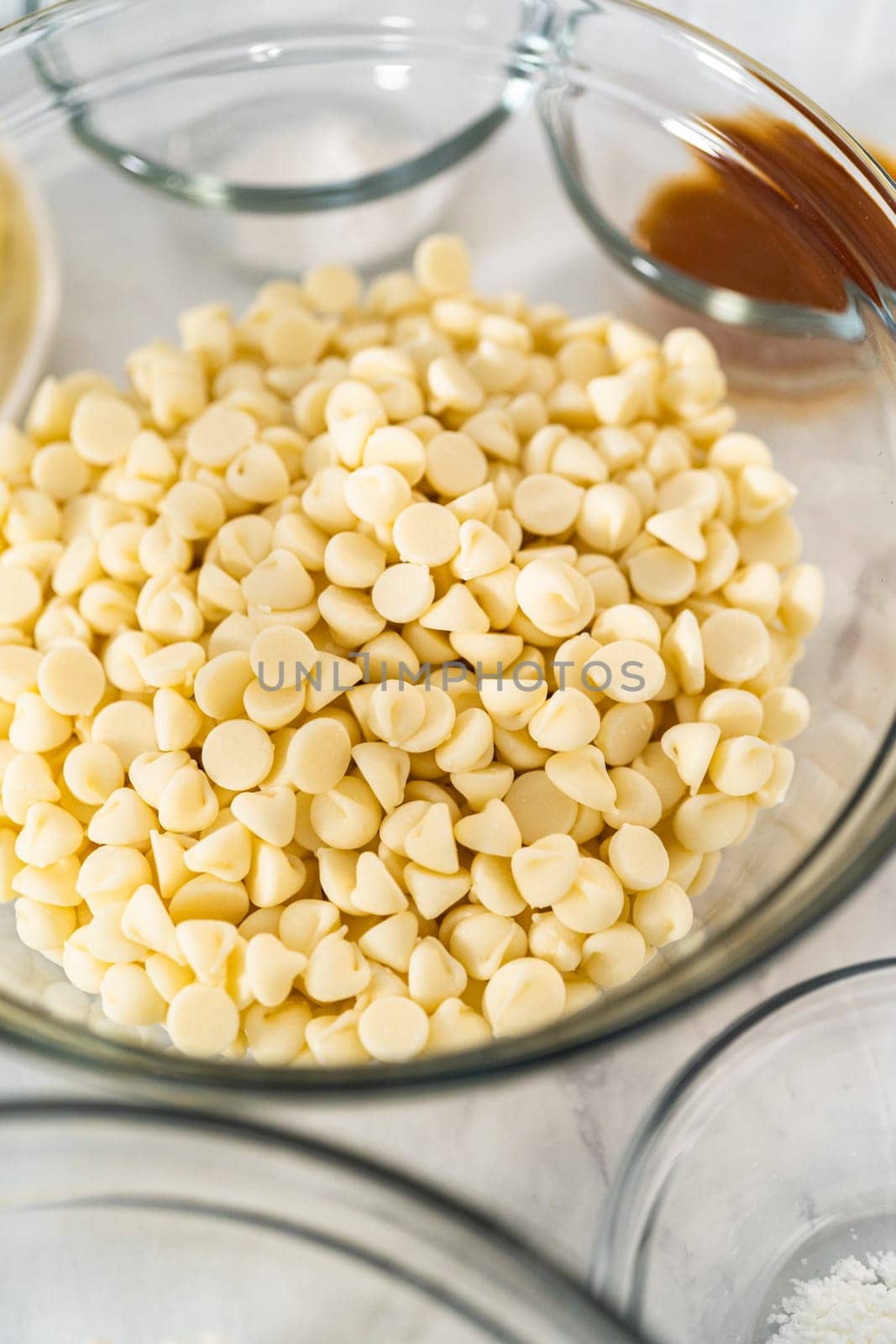 Measured ingredients in glass mixing bowls to prepare white chocolate macadamia nut.