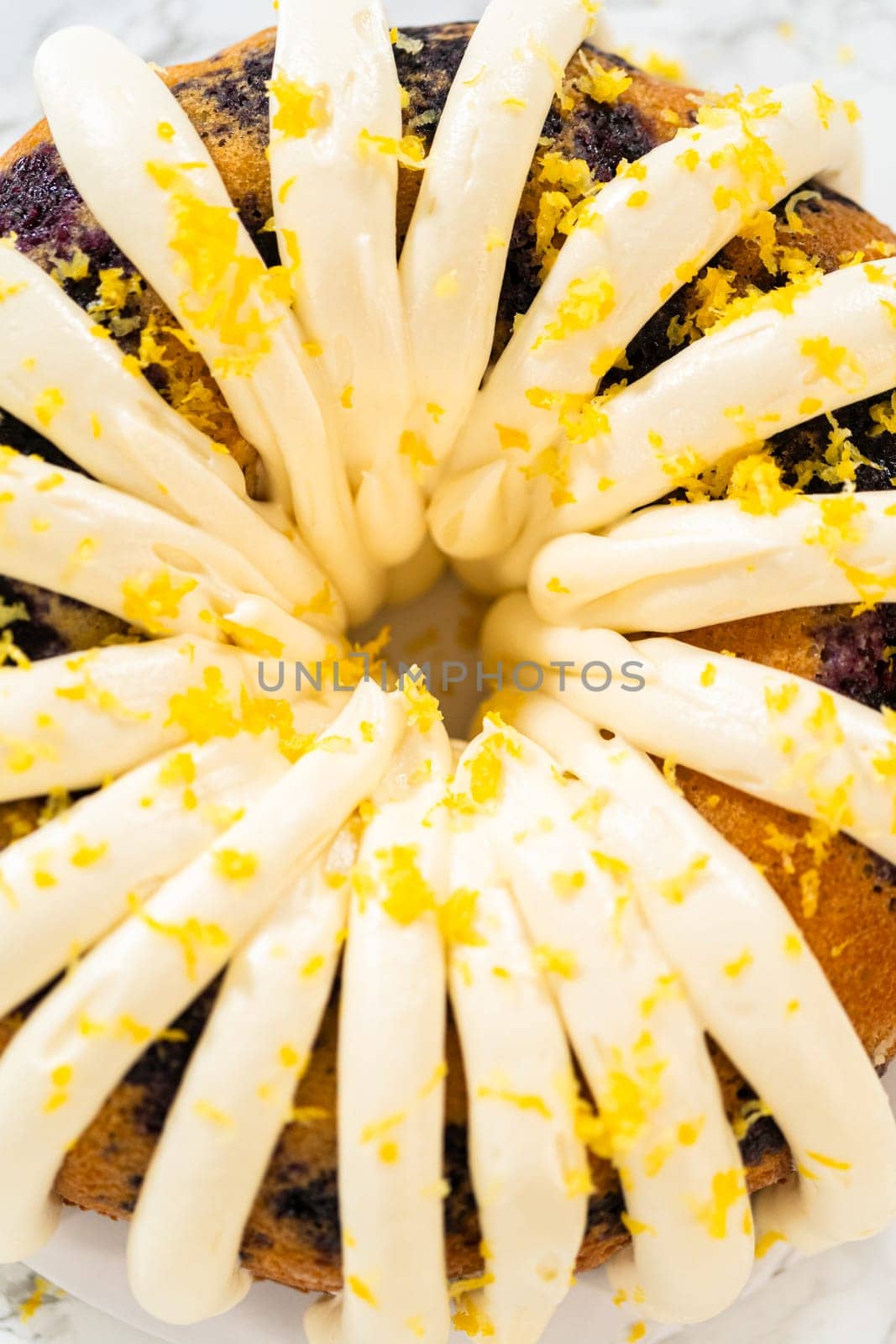 The final stage of this delightful baking journey involves artistically piping the silky cream cheese buttercream frosting atop the cooled bundt cakes, creating an irresistible treat.