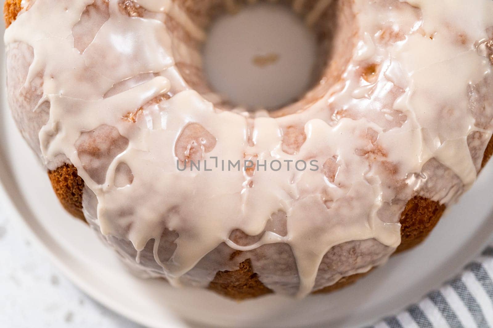 Freshly baked simple vanilla bundt cake with a white glaze on a serving plate.