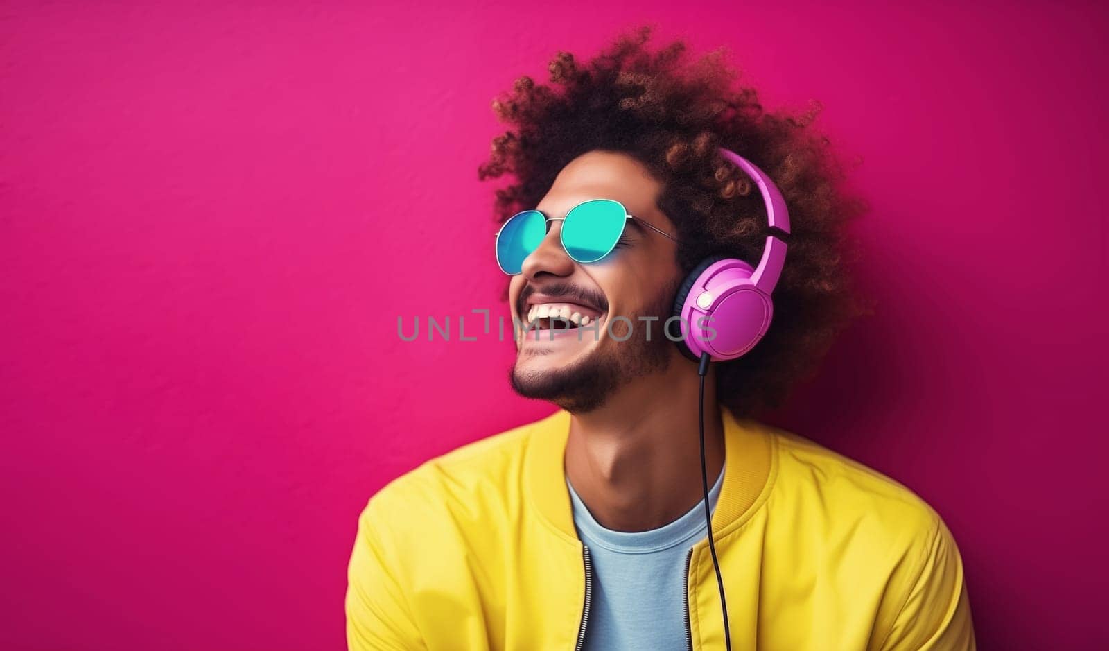 Portrait of happy modern young man listening to music with headphones on colorful studio background