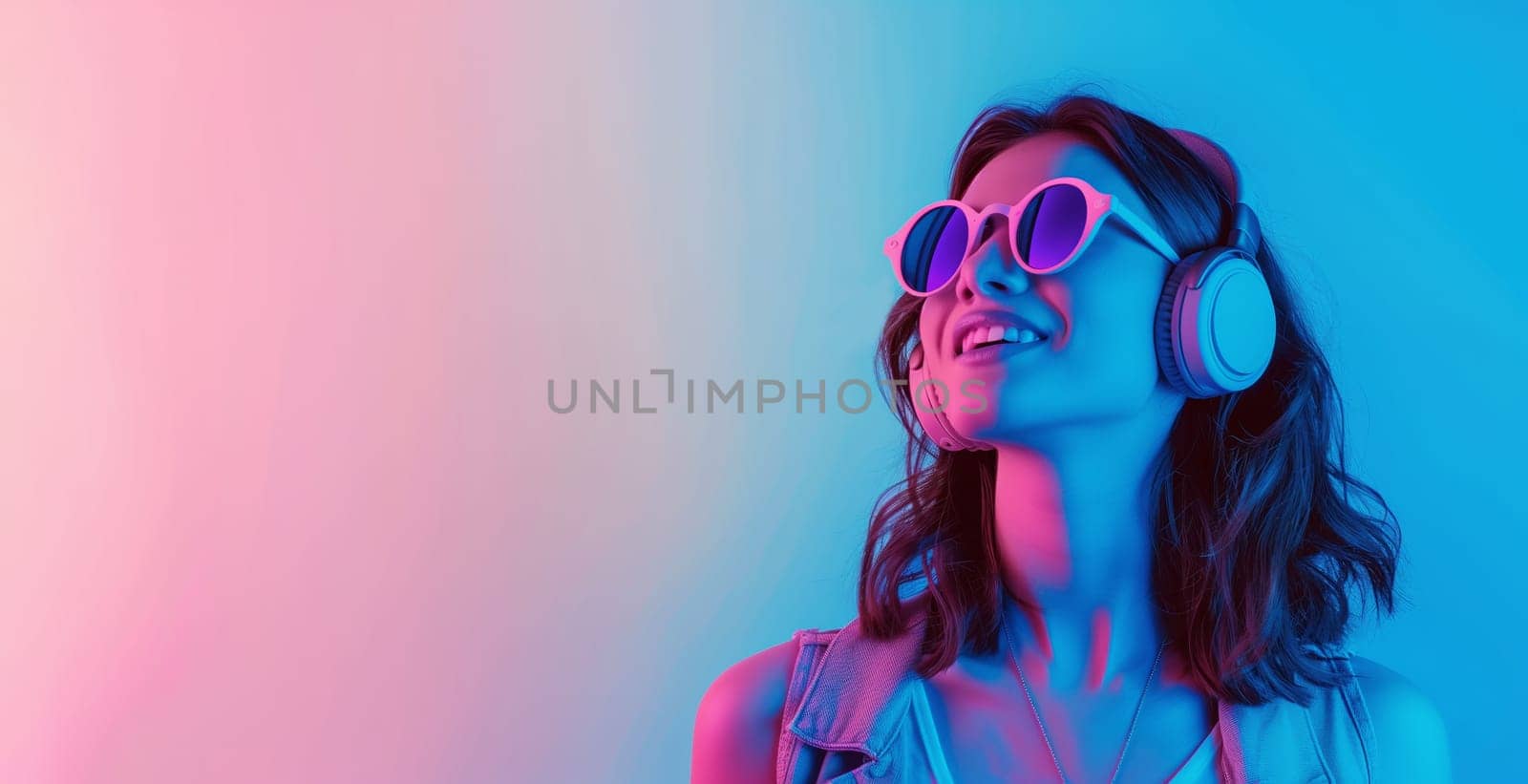 Portrait of stylish modern young woman listening to music with headphones on vivid neon colors background