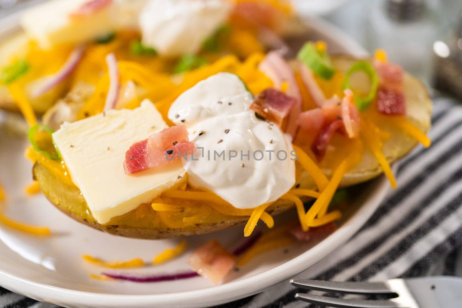 Pressure Cooker Baked Potatoes. Garnished large baked potatoes with butter, sour cream, cheese, and bacon bits on a white plate.