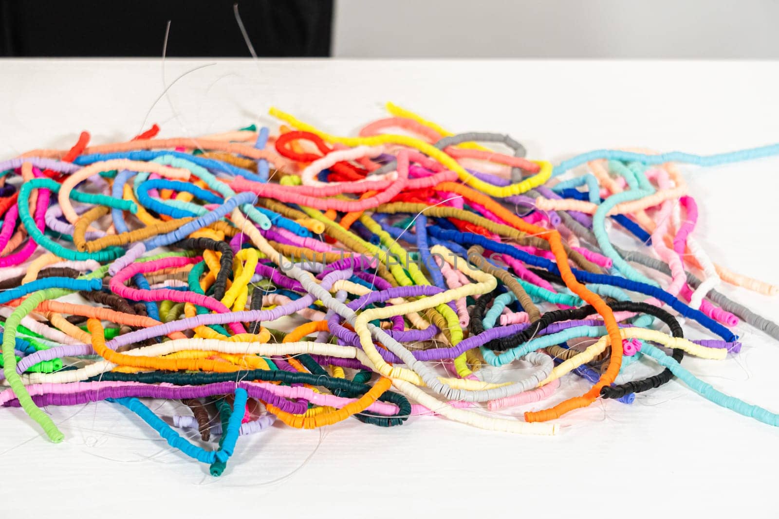 A vibrant collection of clay beads, neatly arranged by color on a white table, ready to inspire young crafters to create their own unique bracelets.