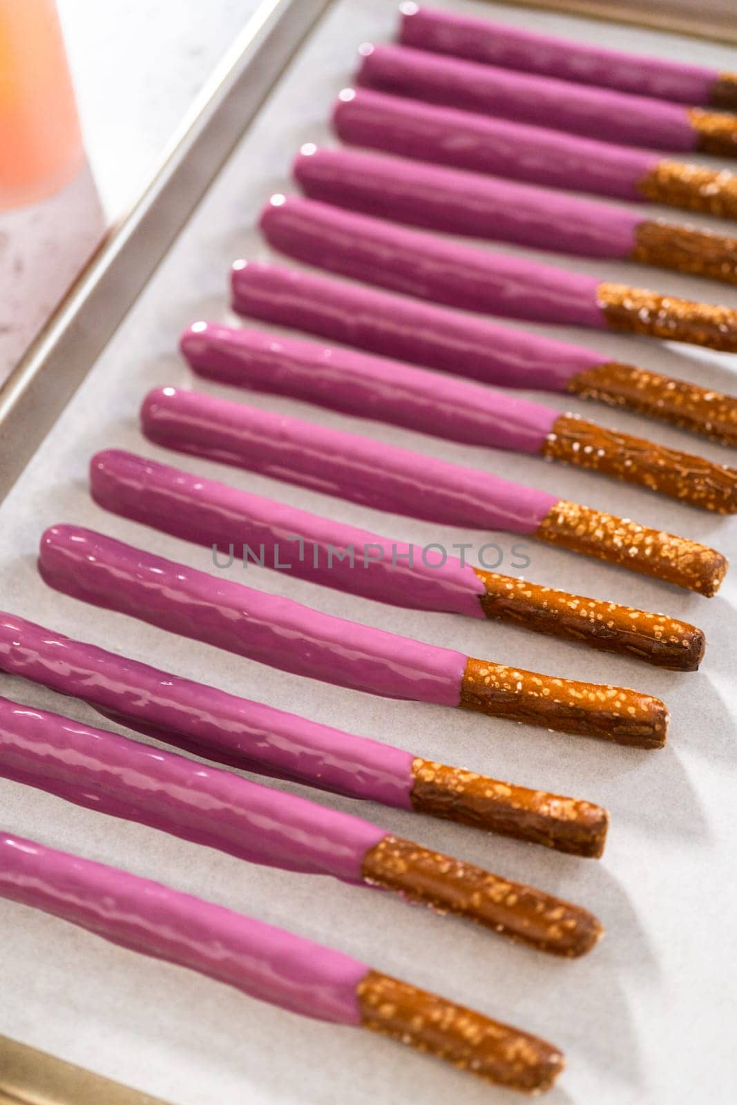 Dipping pretzel rods into melted chocolate to make Halloween chocolate-covered pretzel rods.