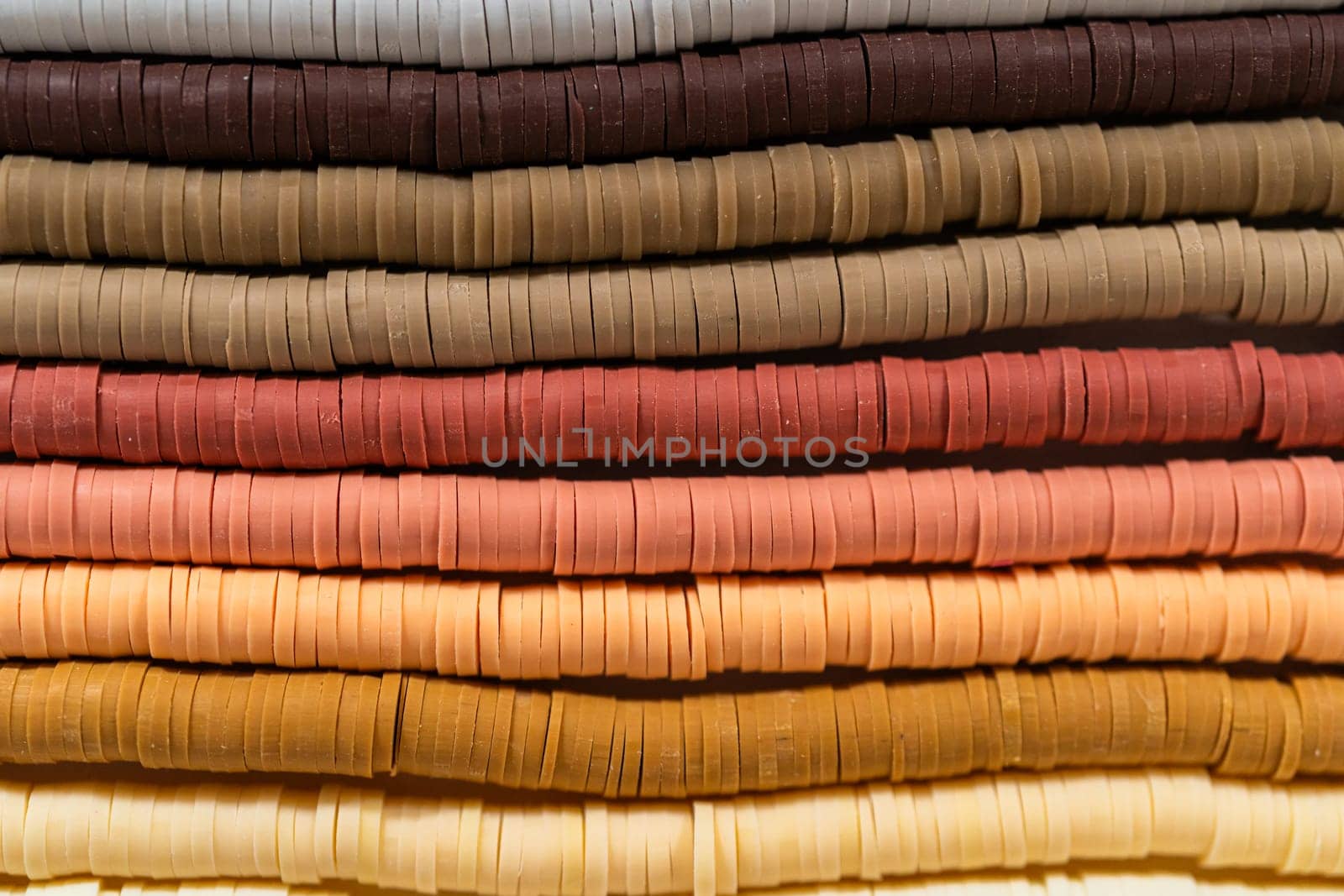 A vibrant collection of clay beads, neatly arranged by color on a white table, ready to inspire young crafters to create their own unique bracelets.