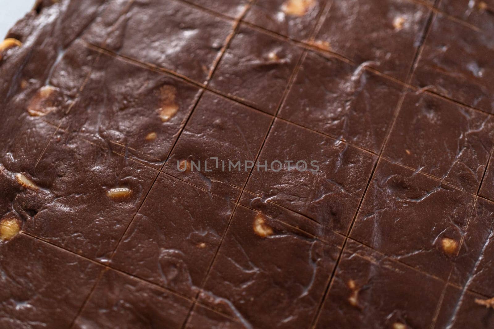 Scoring chocolate macadamia fudge using a wheel dough cutter for cutting into small square pieces.