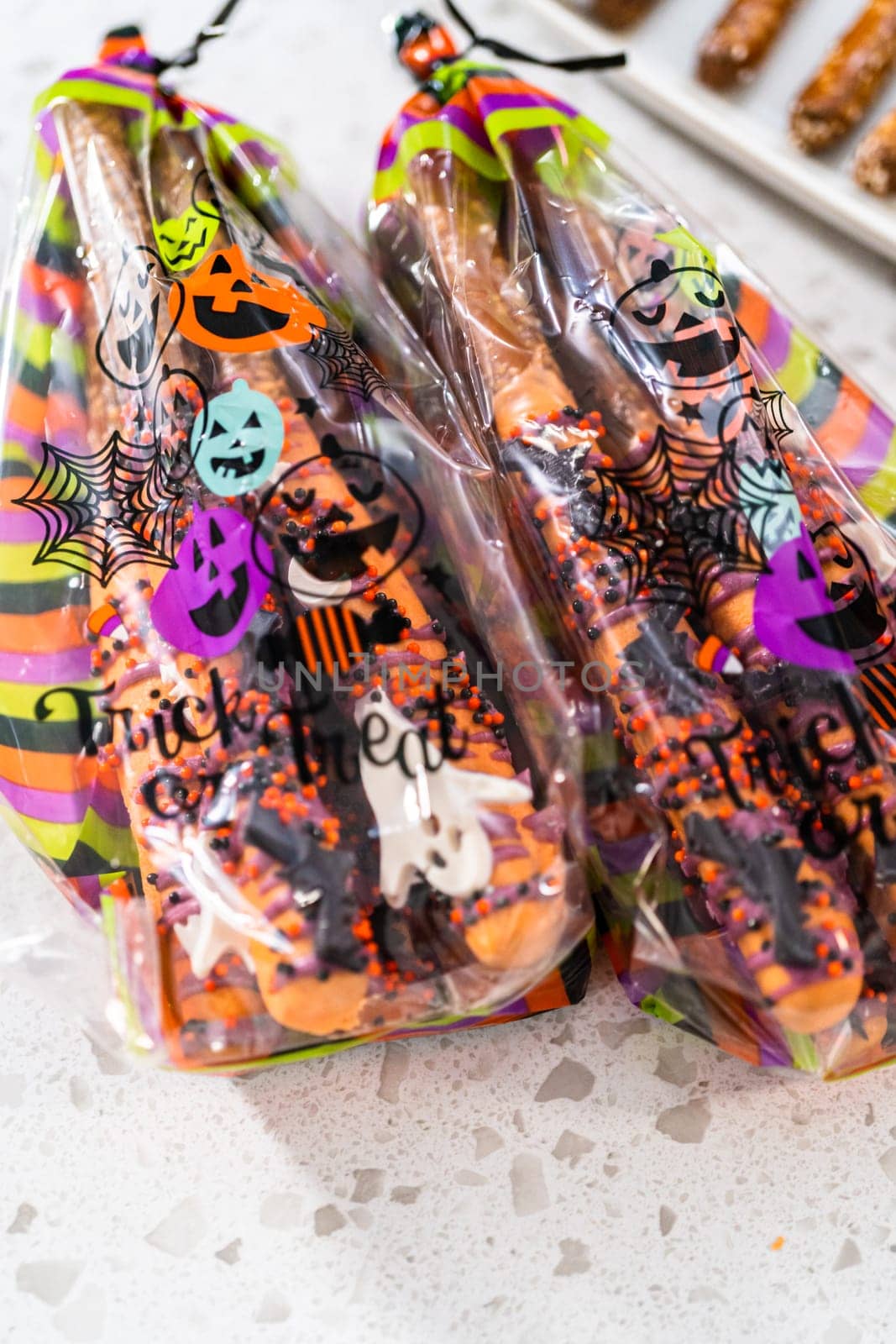 Packaging Halloween chocolate-covered pretzel rods with sprinkles into gift bags.