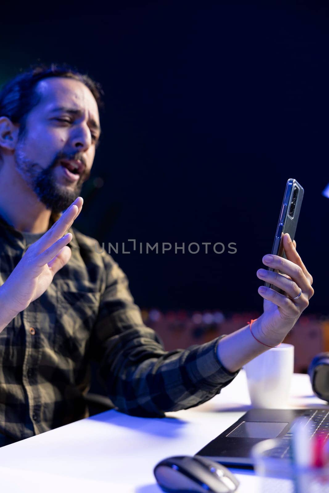 Side view of male university student utilizing his mobile device to conduct a video call conversation. Youthful man using hand gestures in virtual meeting with his colleagues through his smartphone.