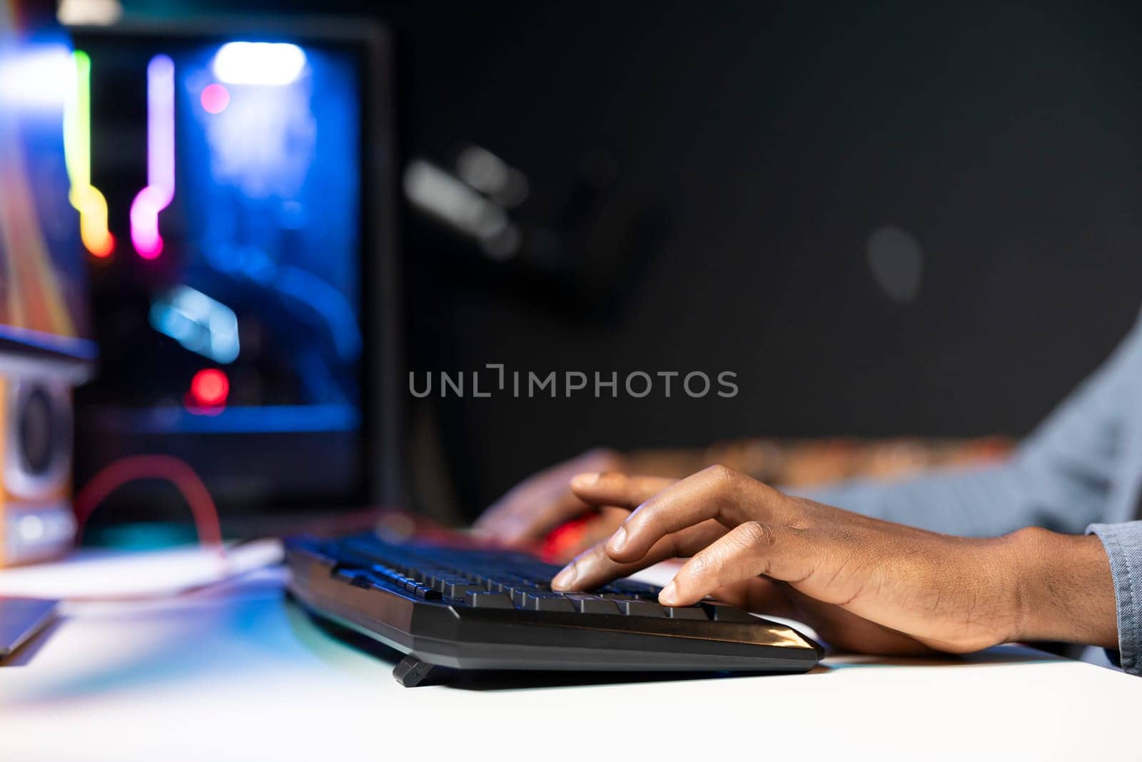 Keyboard used by gamer competing in online multiplayer videogame at home, close up shot. Focus on computer peripheral utilized by man playing on gaming PC in neon illuminated apartment
