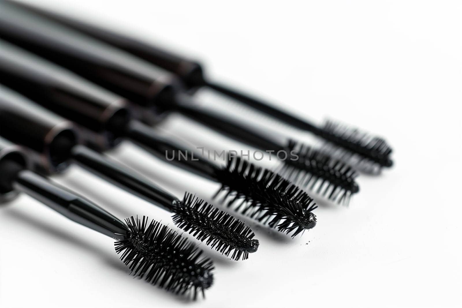 Multiple mascara brushes neatly arranged in a row on a white background.