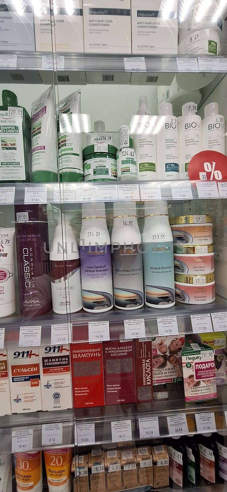 Bobruisk, Belarus - May 1, 2024: A local pharmacy display case showcasing an array of hair masks, shampoos, conditioners, balms, and sun creams on a well-lit morning.