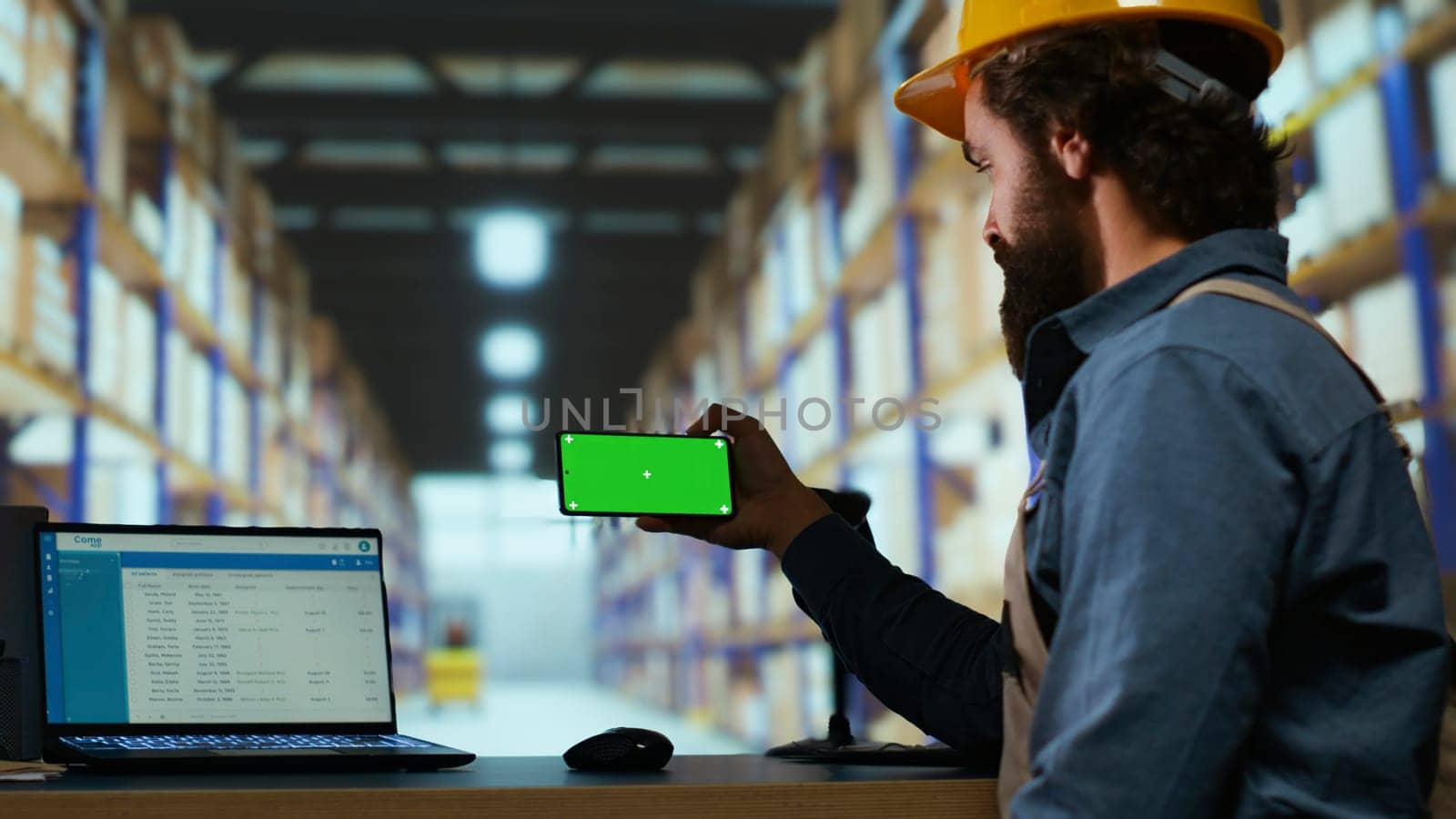 Warehouse manager looks at greenscreen on smartphone display, working on parcel shipment and delivery in industrial depot. Quality control advisor using blank copyspace mockup screen.