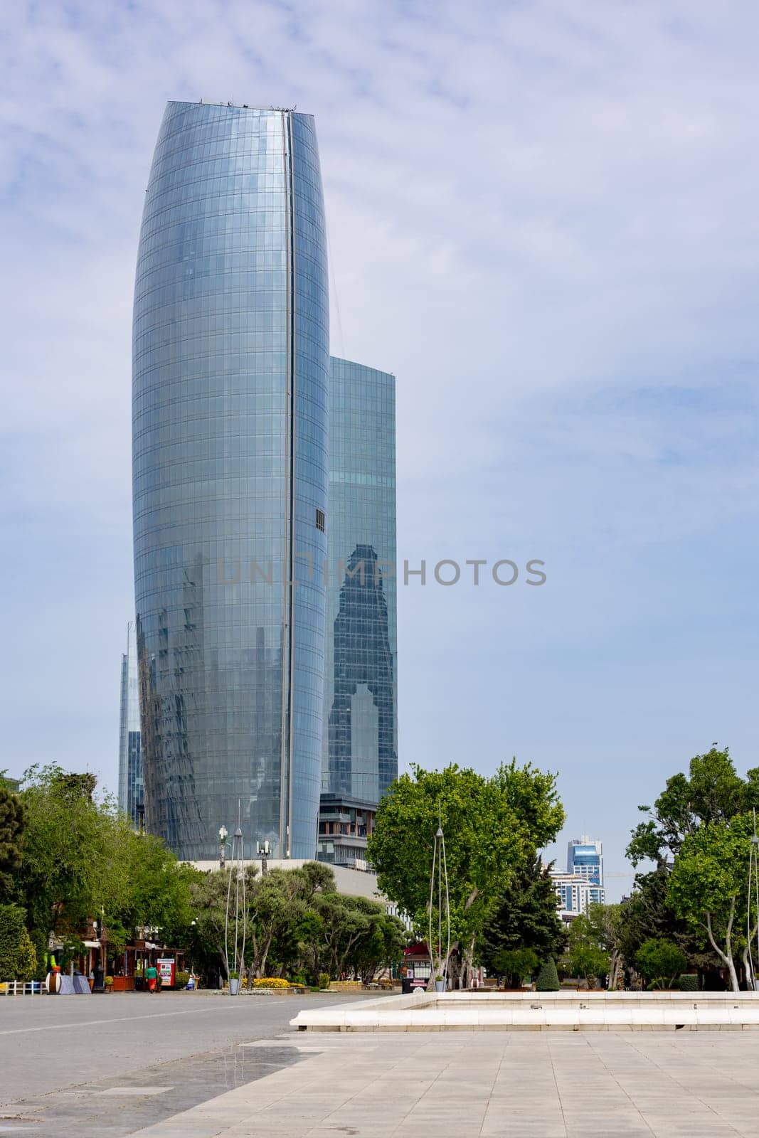 A tall building with a lot of windows and a large glass facade. The sky is clear and the sun is shining