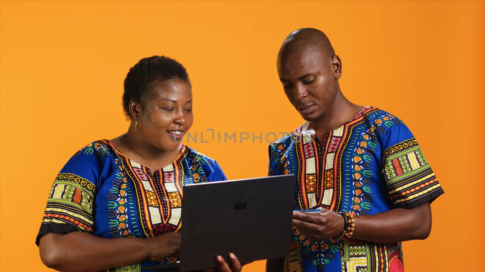 African american woman buying clothes online on laptop, doing shopping session and typing credit card details on webpage. Married couple looking at items on sale, banking purchase.