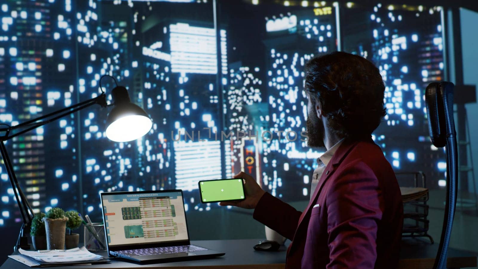 Shareholder checks greenscreen on mobile device display, sitting at his posh workstation in skyscraper building and planning business growth. Gentleman looks at isolated copyspace screen.