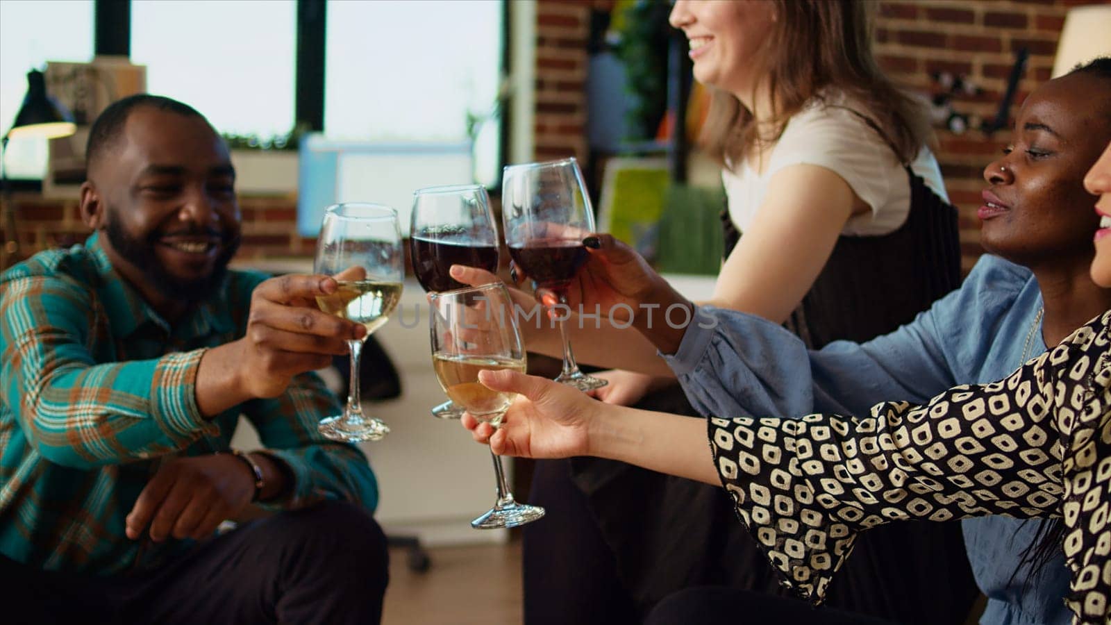 Multiracial group of friends talking with each other in brick wall apartment living room by DCStudio