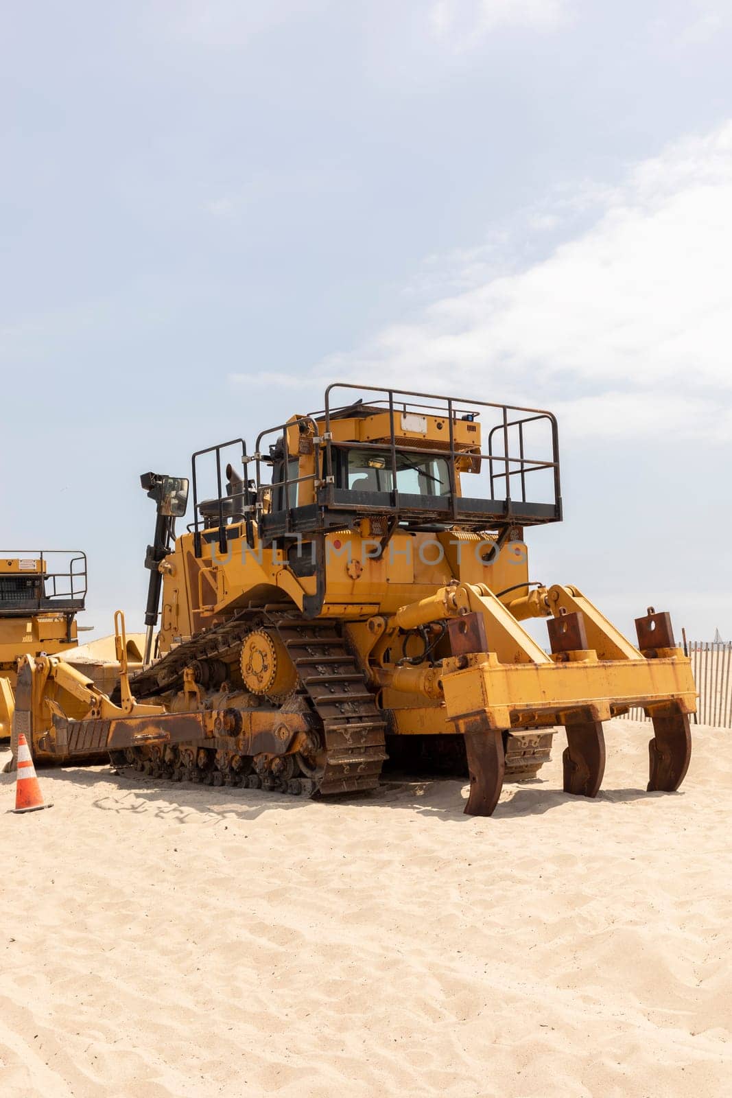 Yellow Crawler Dozer On Sandy Beach, Blue Sky On Background. Bulldozer Builds Roads. Construction And Landfill Equipment And Machinery. No People. Vertical Plane. High quality photo
