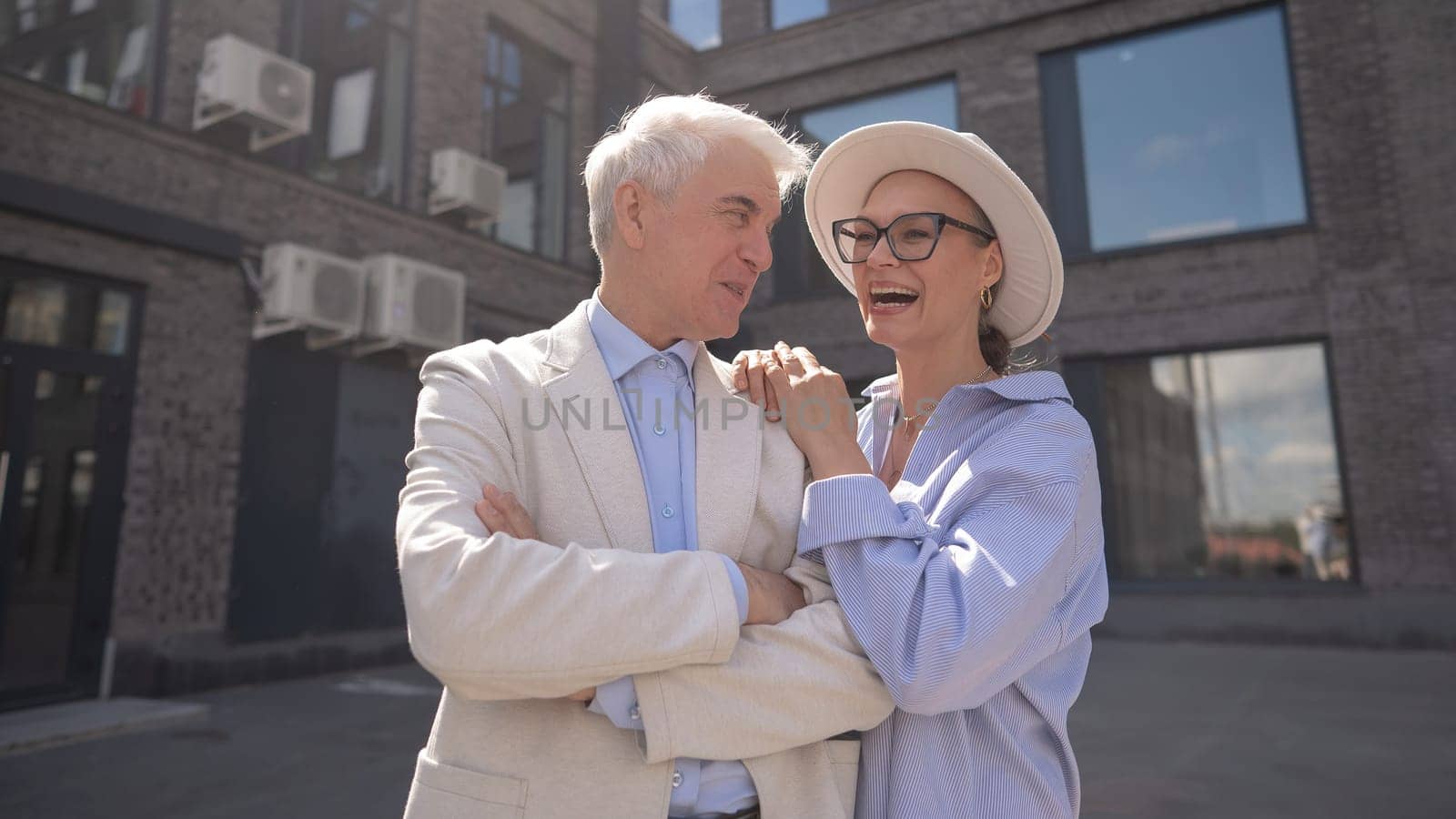 An elderly couple in love walks through the city. Portrait of a stylish gray-haired man and woman. by mrwed54