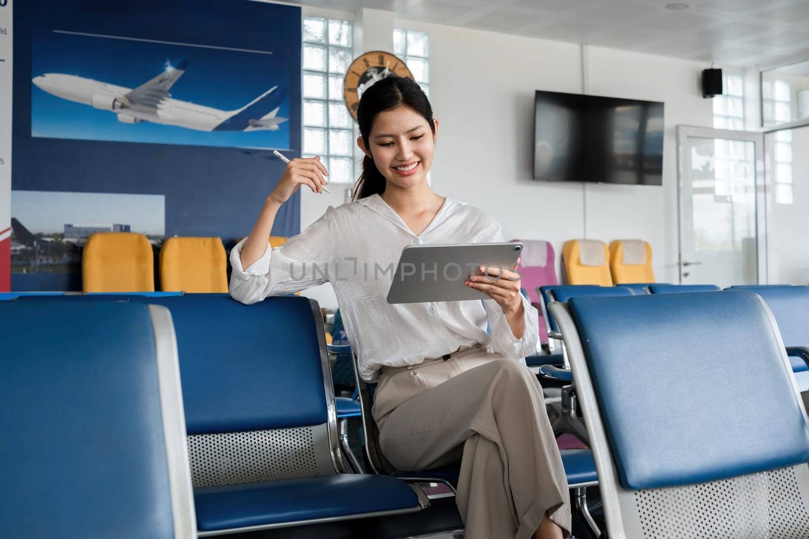 Young woman waiting at airport with luggage and tablet. Concept of travel and technology by wichayada