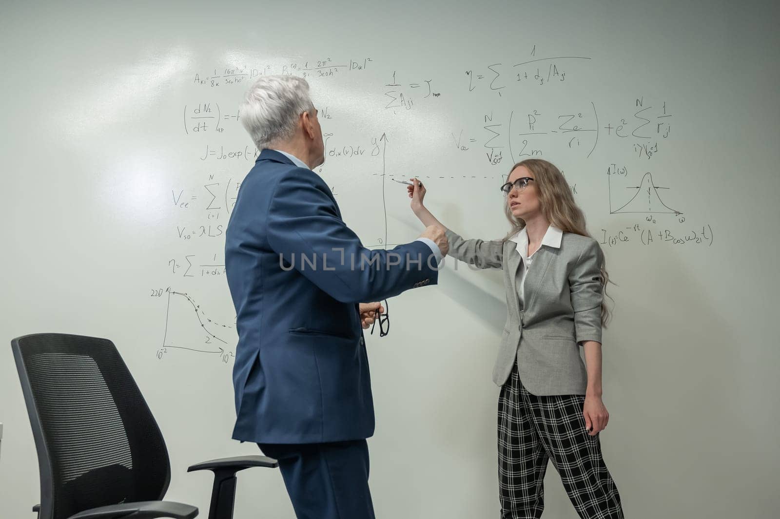 Female student answers a question from an elderly professor at a white board