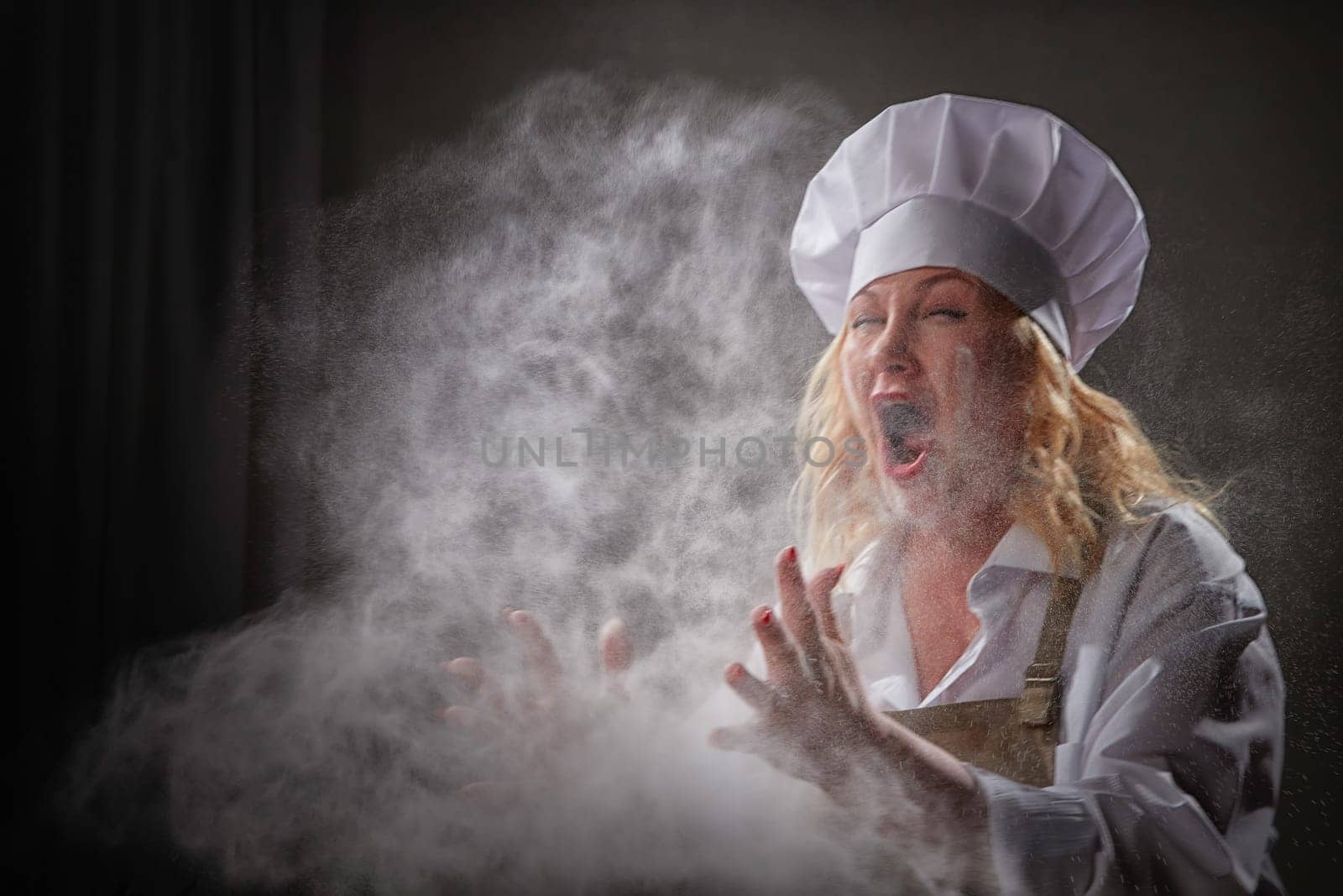 Fat funny female cook in a hat and apron posing and taking selfie in the kitchen with flour. Cooking, body positive, cloud, smoke, flour