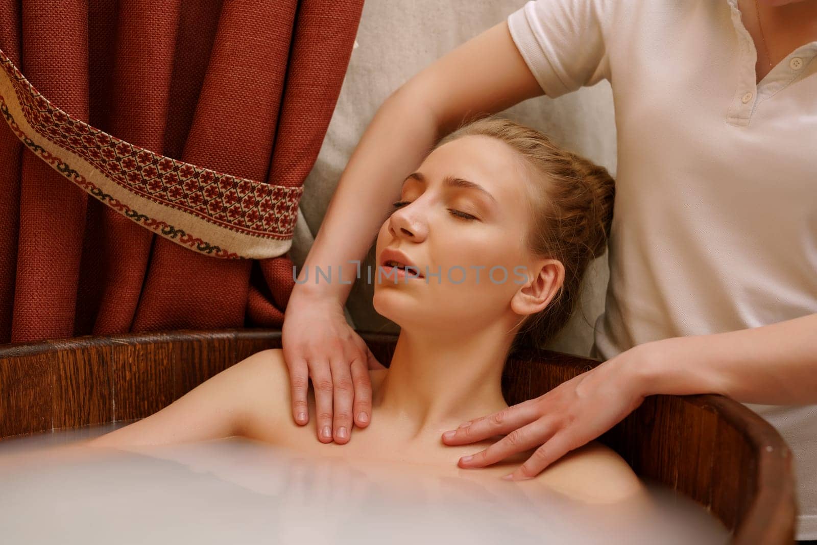 In spa. Girl's shoulders massaged during she taking bath