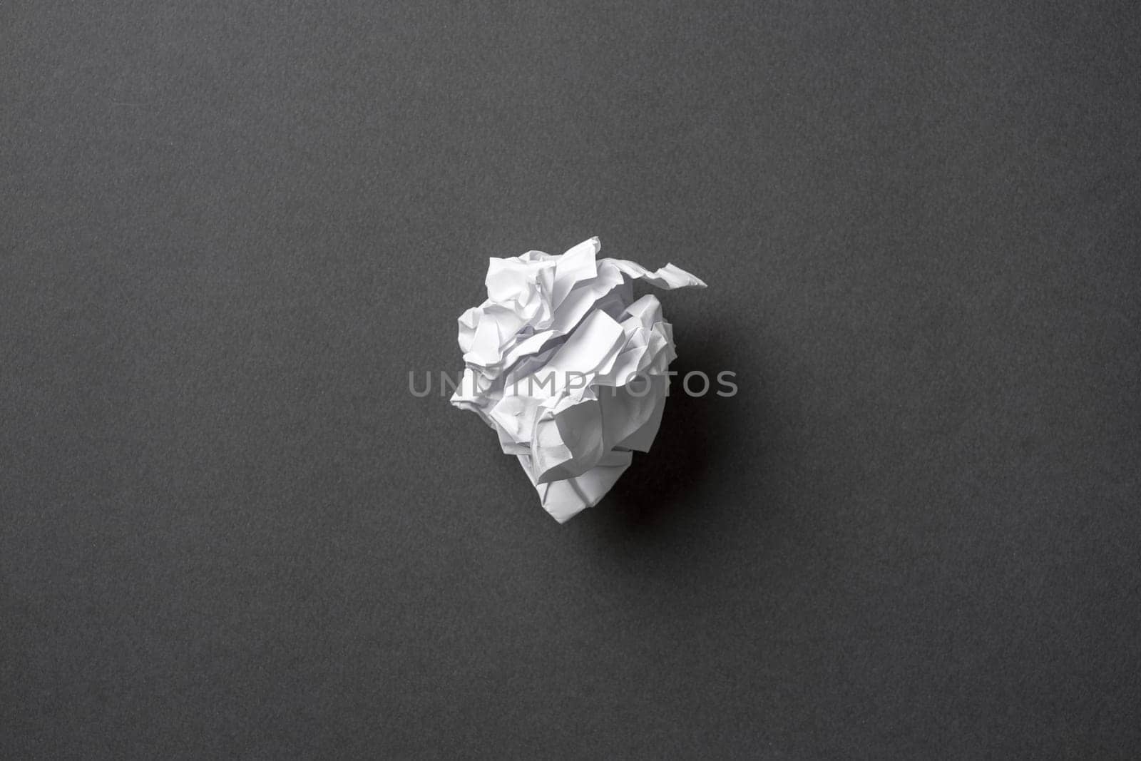 White paper crumpled into a ball on a dark gray background