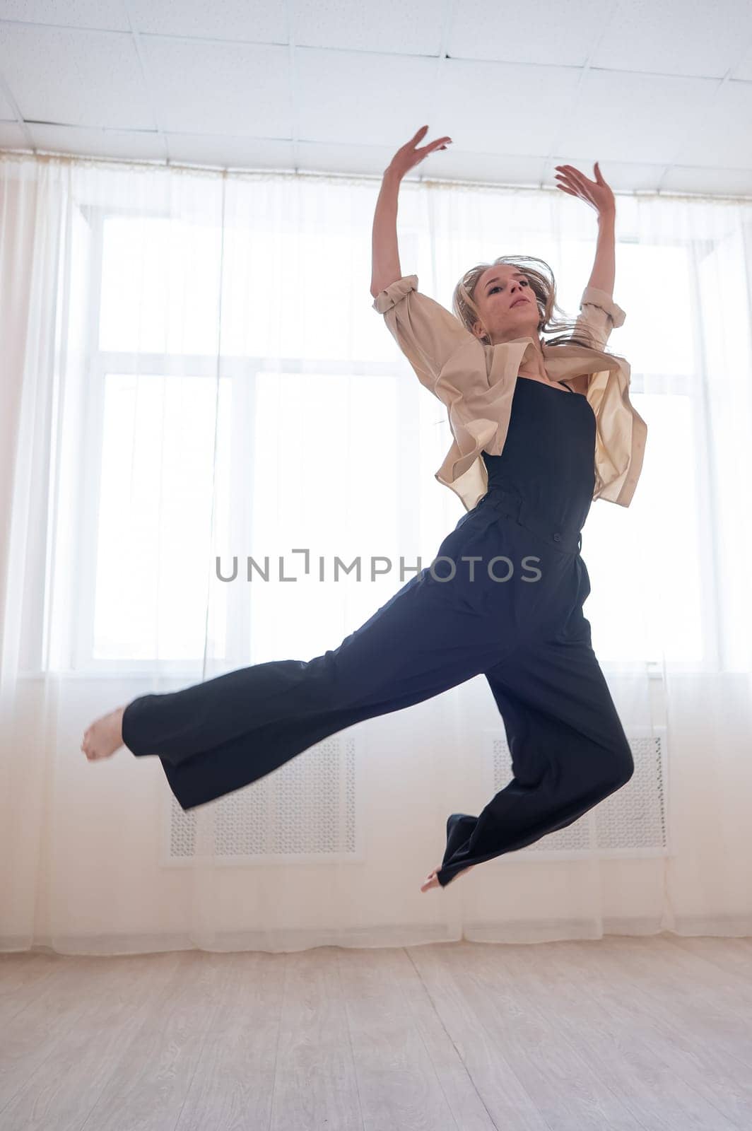 Caucasian woman dances contemporary in ballet class. Dancer in a jump. Vertical photo. by mrwed54