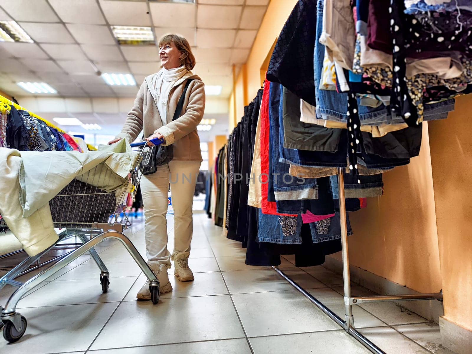 Middle-Aged Woman Selecting Clothes During Shopping Trip. Shopping for apparel in clothing store. Shopaholic