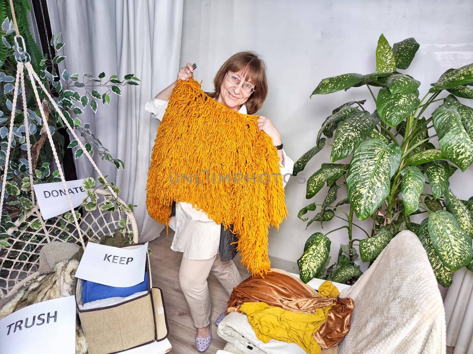 Middle-Aged Woman Sorting Belongings With KonMari Method. Mature woman categorizes items into keep and discard piles