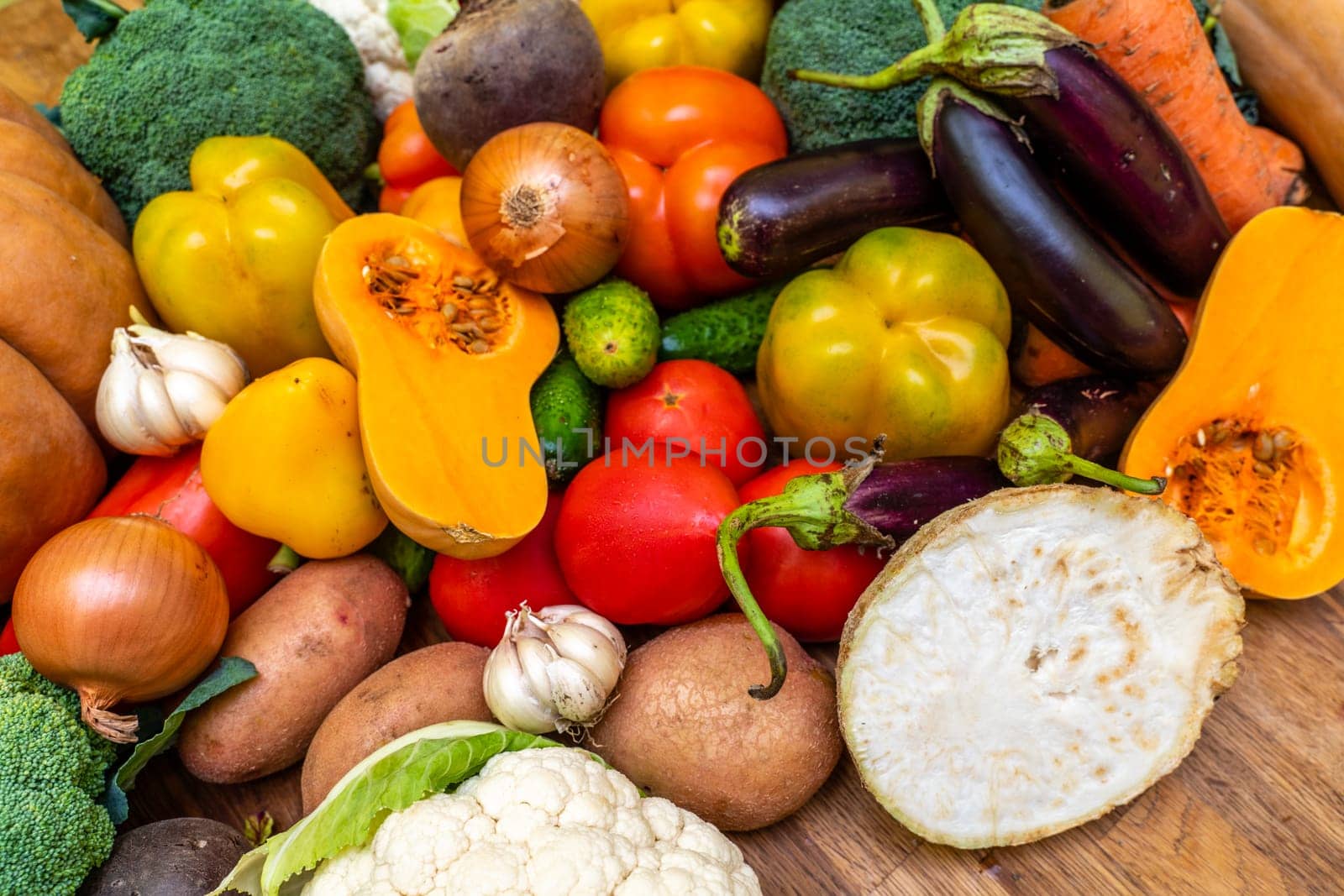 Various vegetables are laid out on a wooden table. Large assortment of vegetables food. pumpkin cabbage broccoli pepper tomatoes carrots and others.