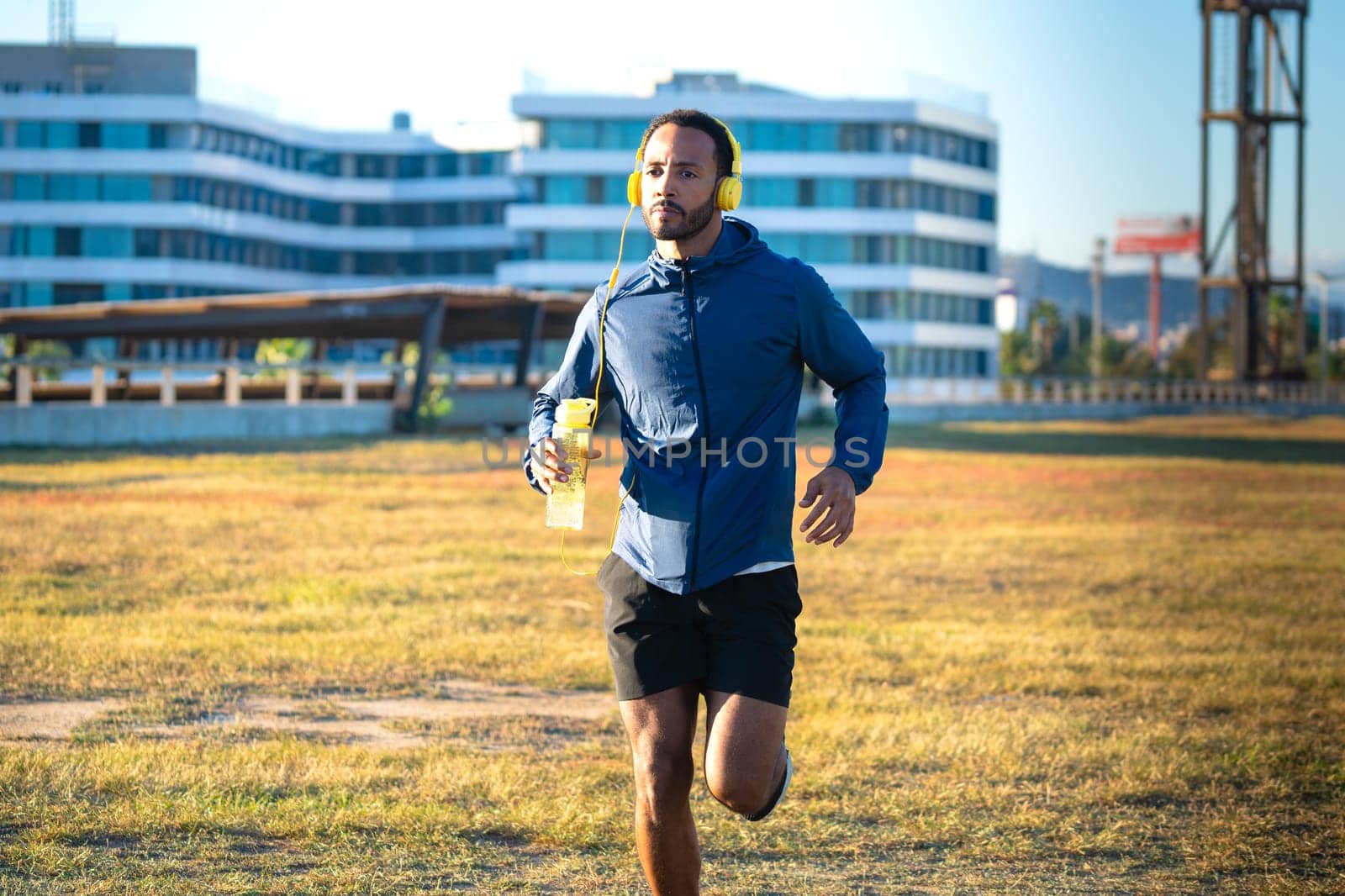 Young latin athlete with headphones training outdoors.