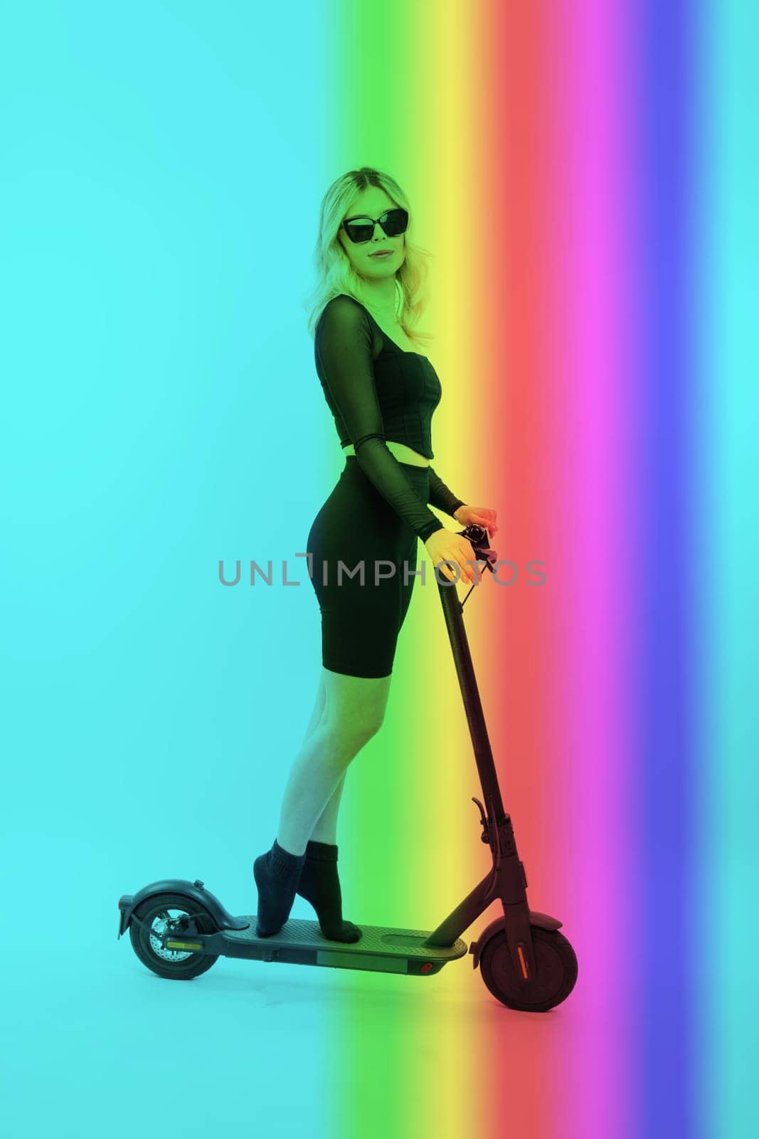 Beautiful emotional young female in sport clothes on electric scooter on red and white background by Zelenin