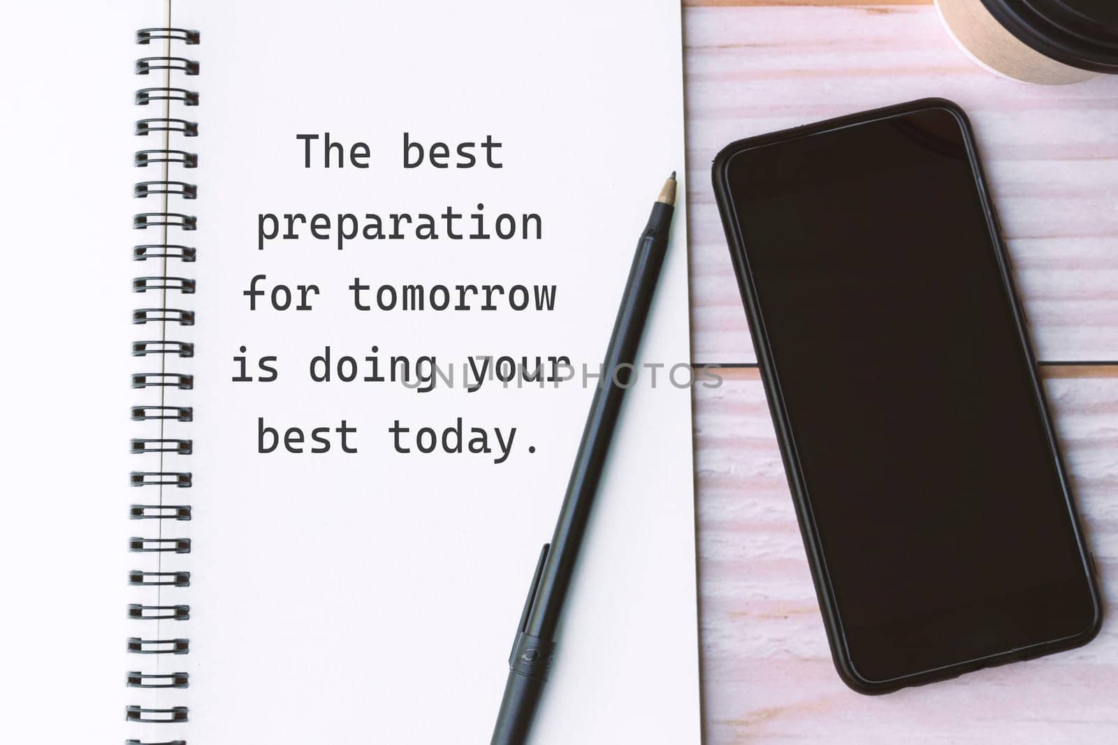 Motivational quote written on notebook with pen, smartphone and coffee on wooden background - The best preparation for tomorrow is doing your best today.