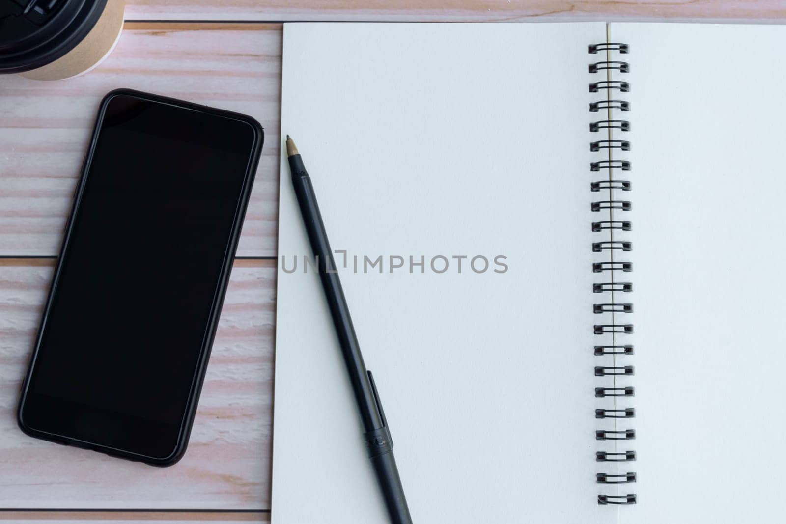 Note book with pen, smartphone and coffee on wooden desk. Directly above. Flat lay. Copy space.