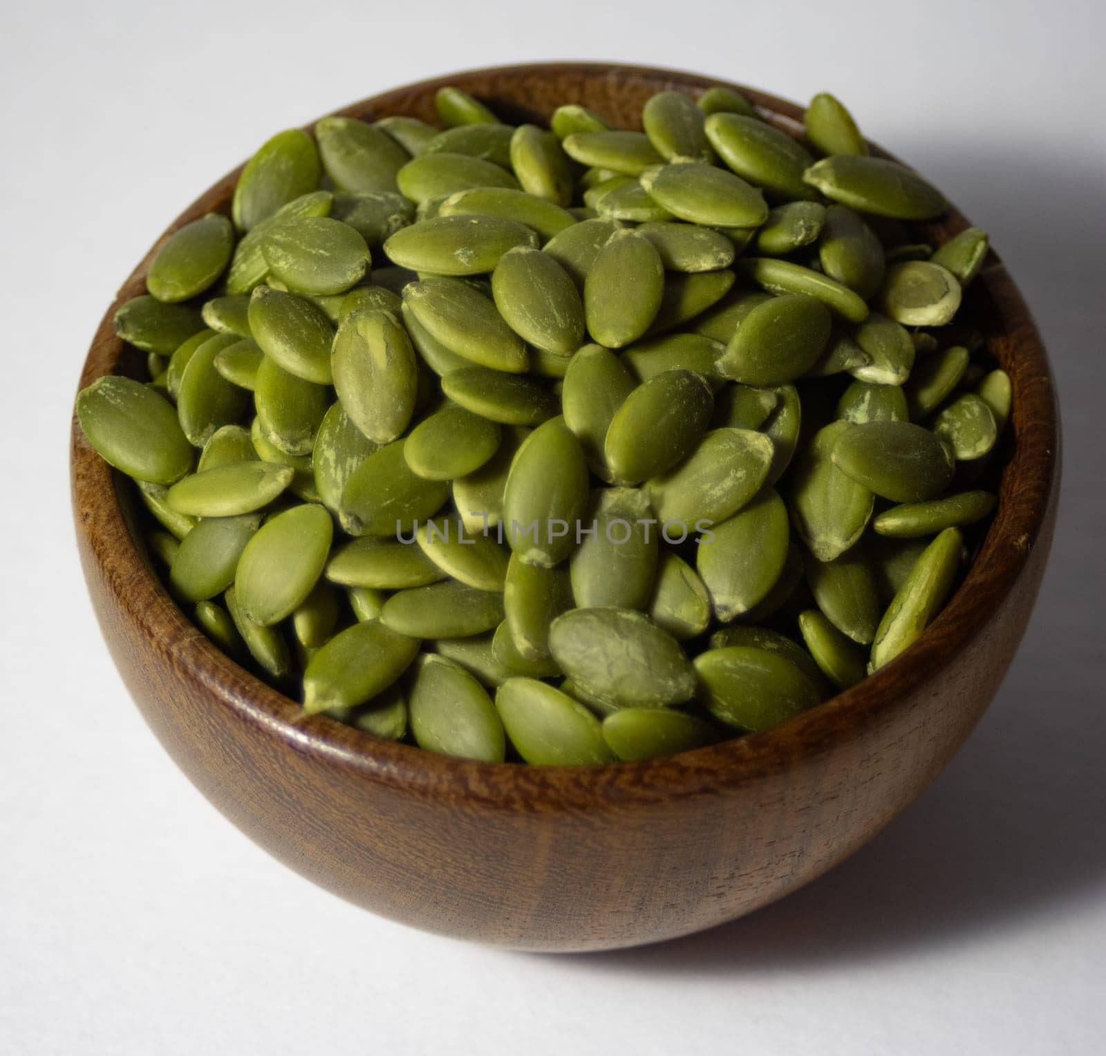 Zenithal photo of wooden bowl with pumpkin seeds ,isolated, by VeroDibe