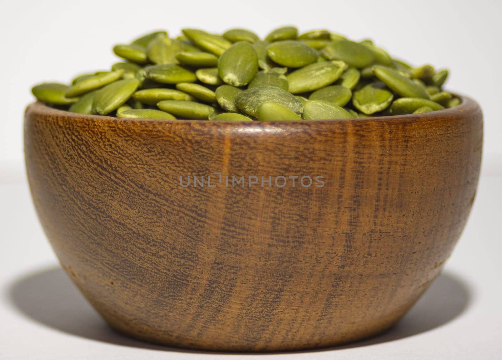 Wooden bowl with pumpkin seeds ,isolated, White background. by VeroDibe