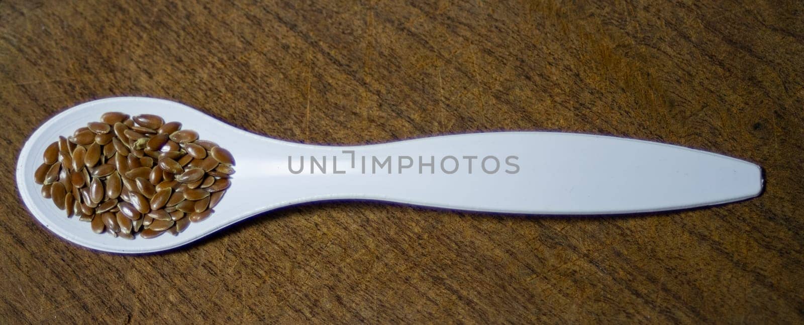 White spoon with linseed on wooden background..Healthy food. by VeroDibe