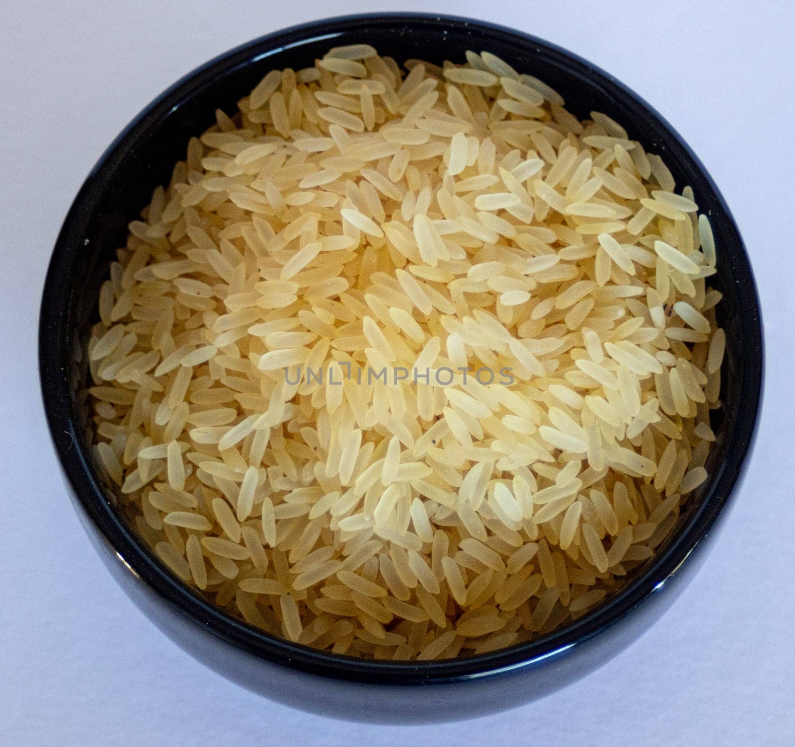 Zenithal phot of a bowl with yellow parboiled rice on white background. by VeroDibe