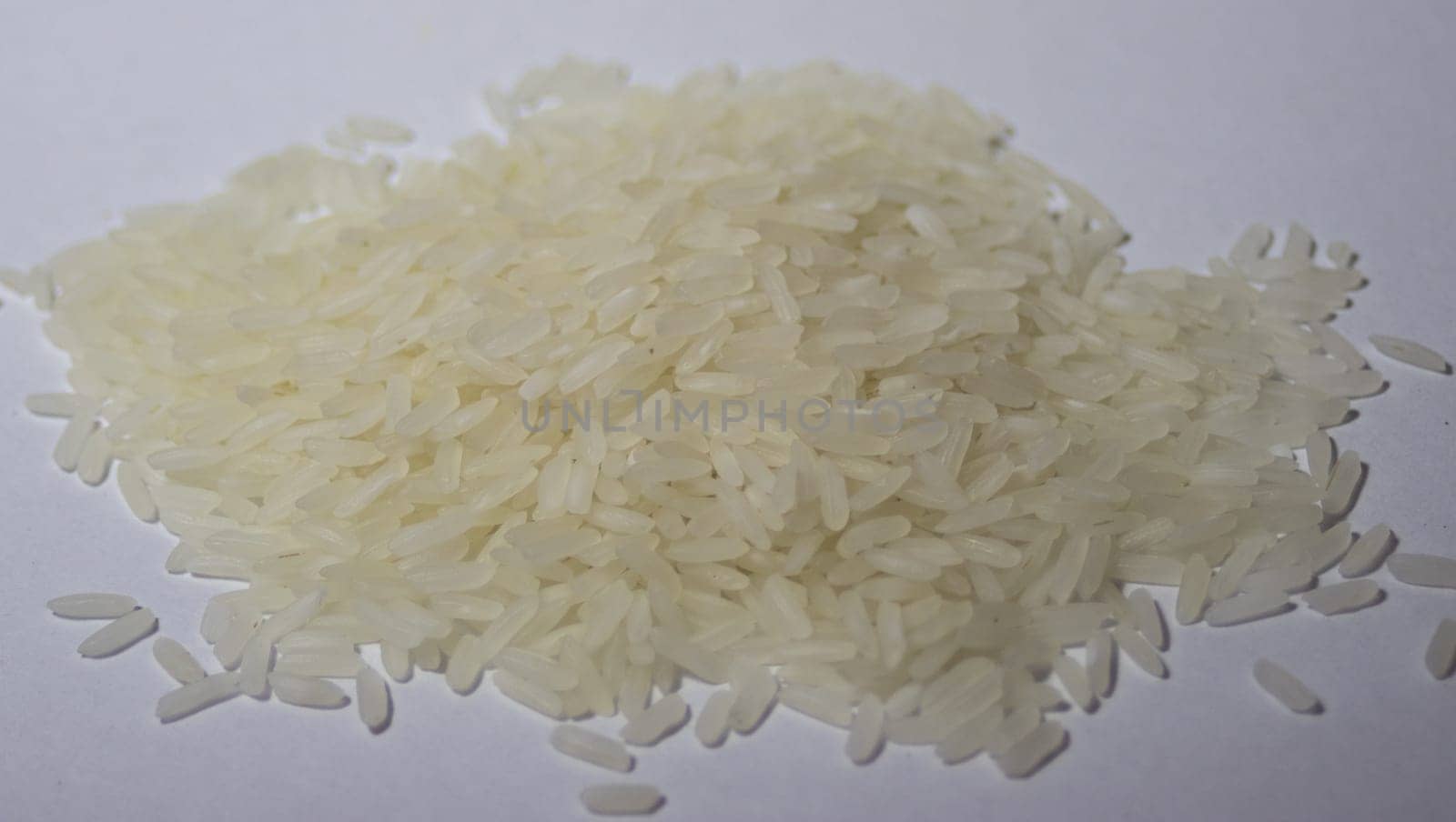 Very close-up photo of a pile of rice grains on white background. by VeroDibe