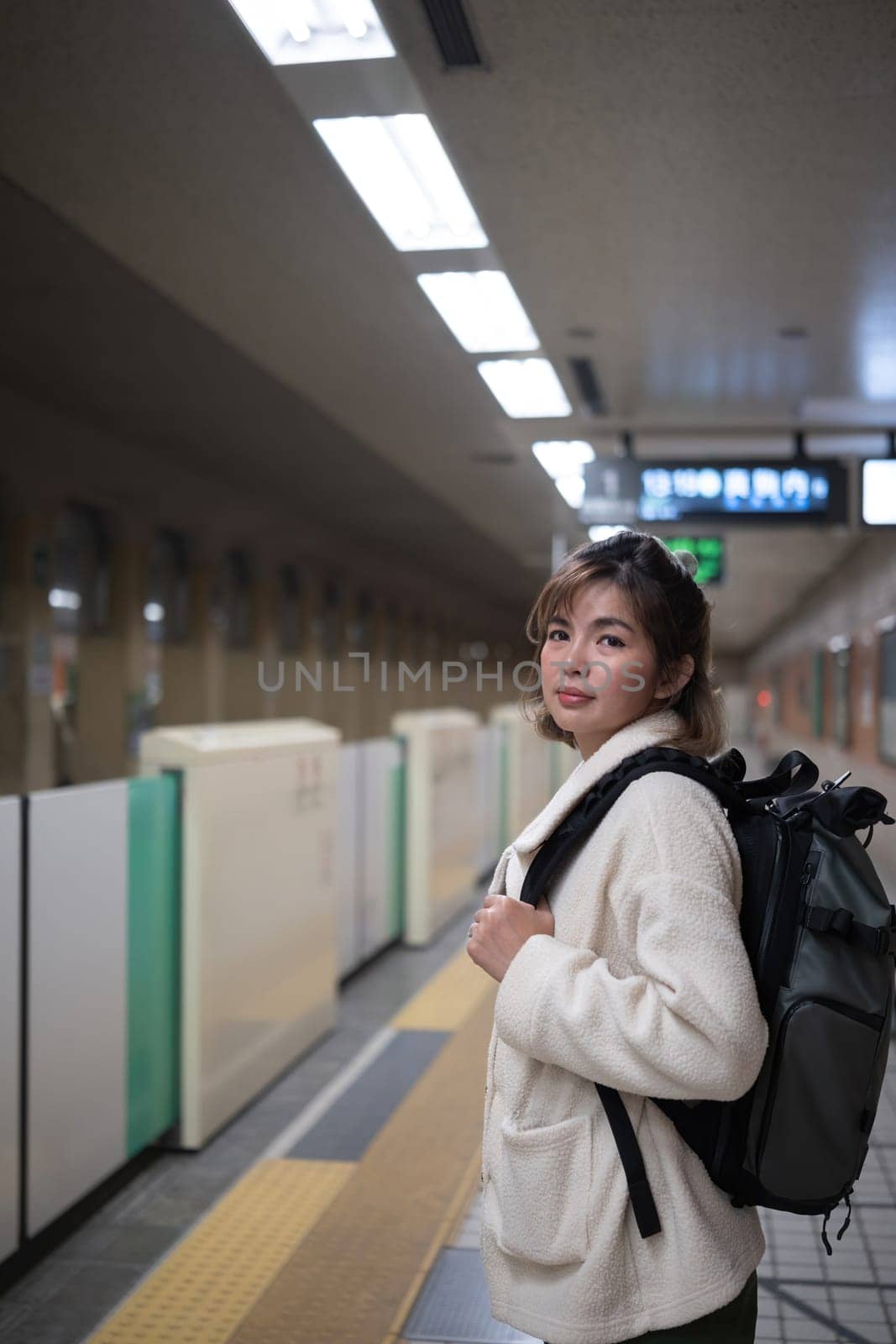 Woman with backpack waiting in subway station. Concept of travel and urban commuting.