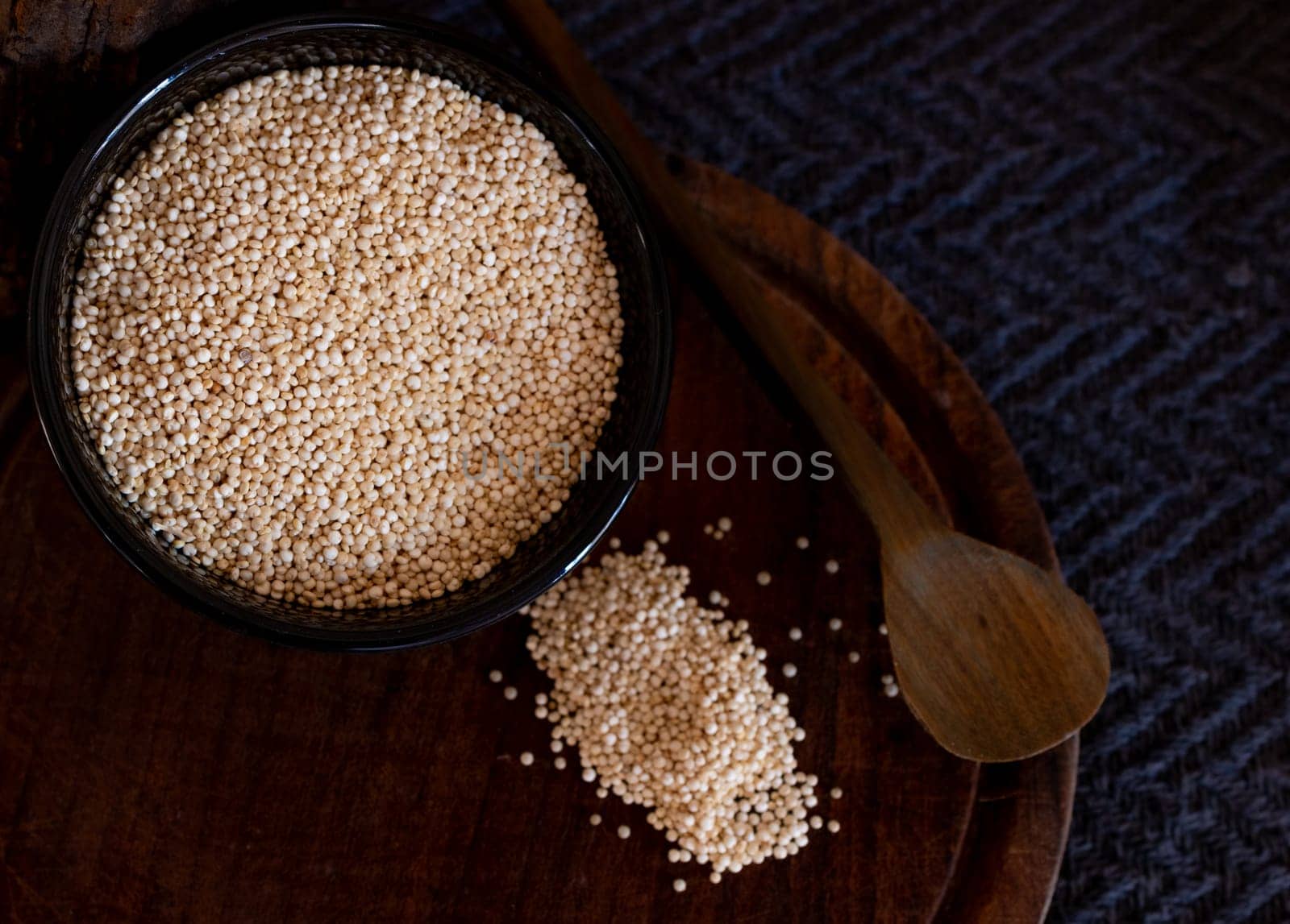 Grais of quinoa in black bowl ,some seeds on wooden board by VeroDibe