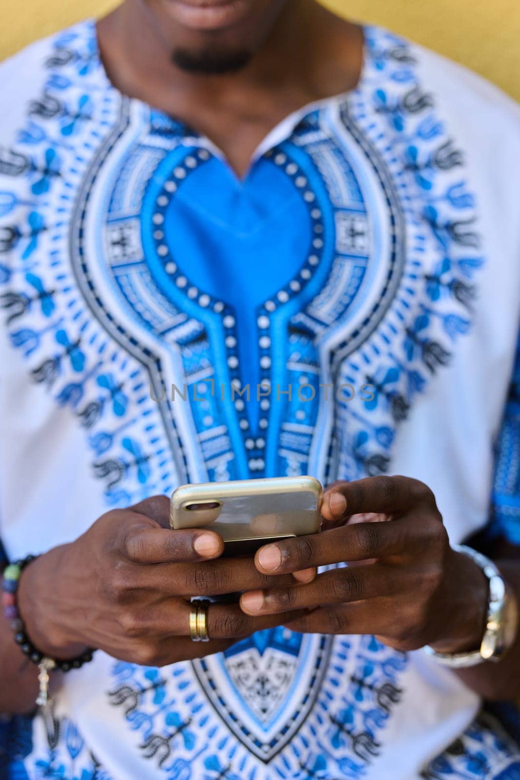 African American teenager adorned in traditional Sudanese clothing, seamlessly navigating the digital world with a smartphone in hand.