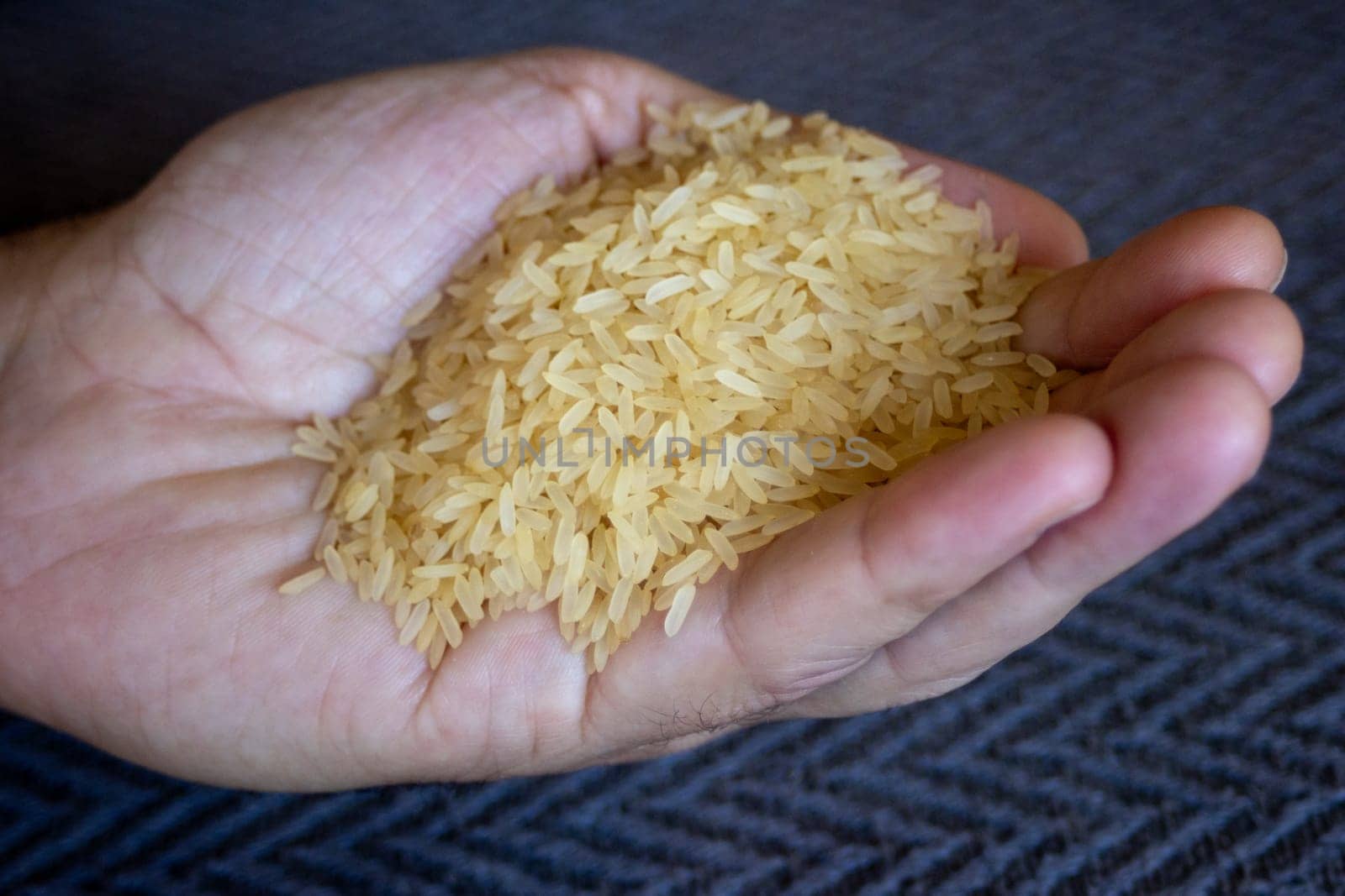 Man hand holding yellow rice grains .Very close up photo.Healthy eating. by VeroDibe