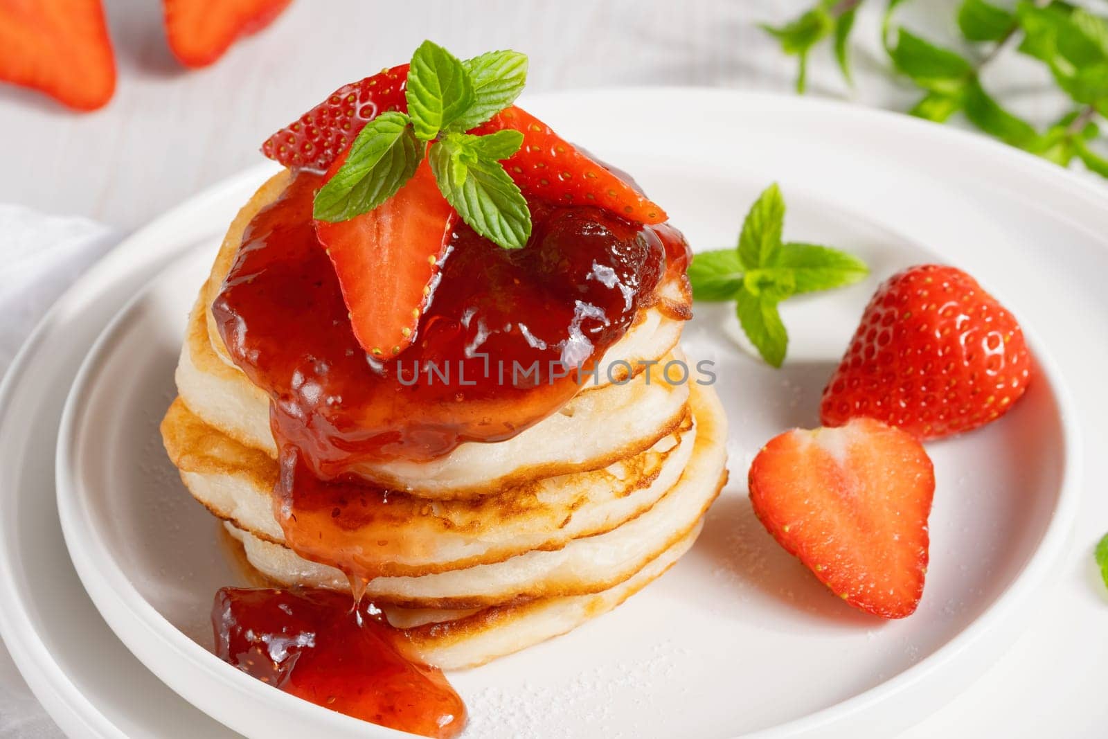 Mini pancakes with strawberry jam and strawberries.