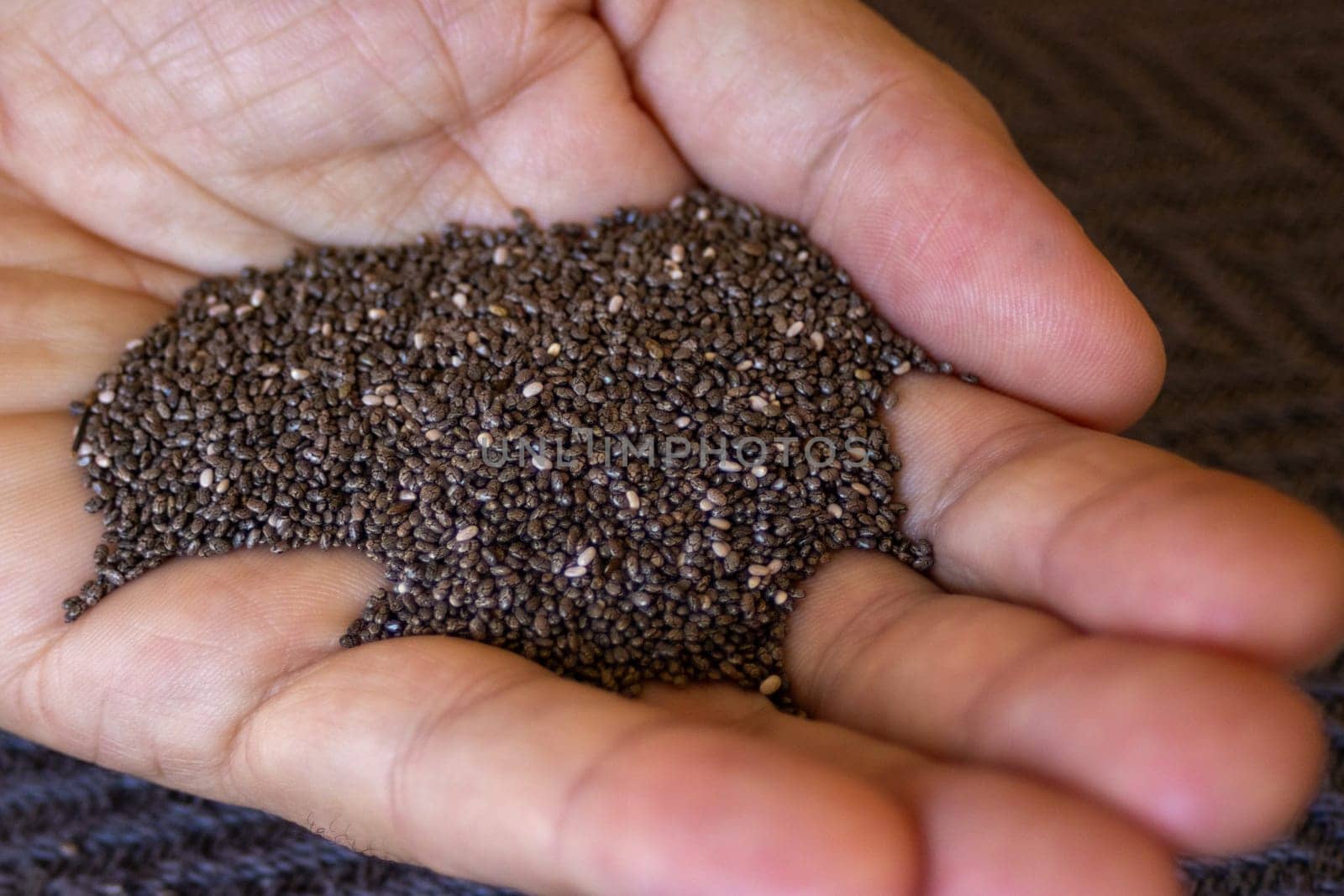 Man's hand holding chia seeds. Close-up photo. by VeroDibe